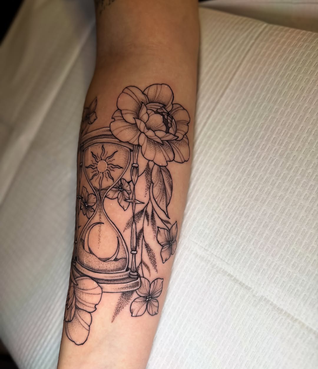 Hourglass and flowers dotwork tattoo on the forearm by McKenna