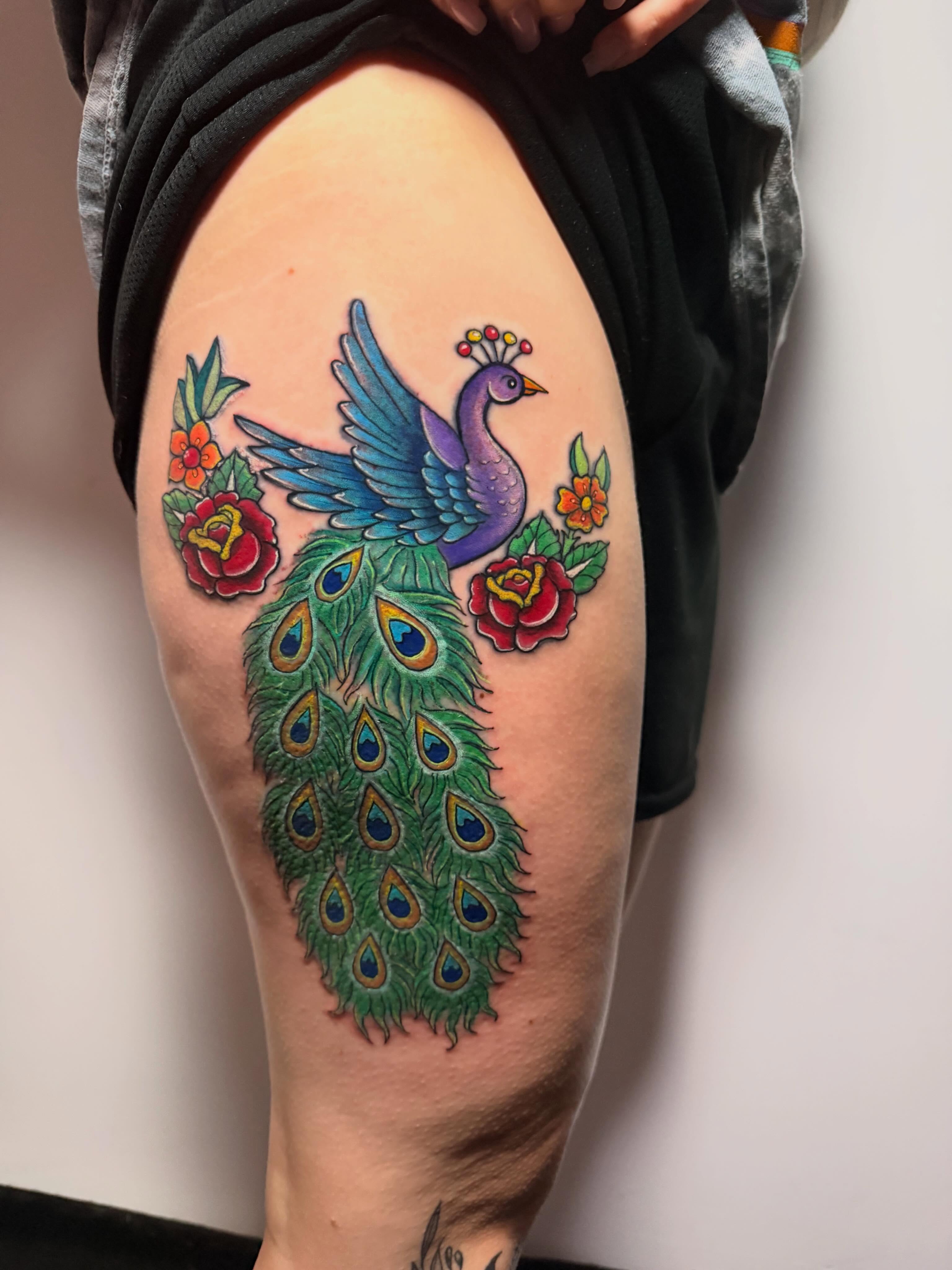 Peacock and flowers American traditional tattoo on the thigh by Gabrielle Frelak, York, Pennsylvania