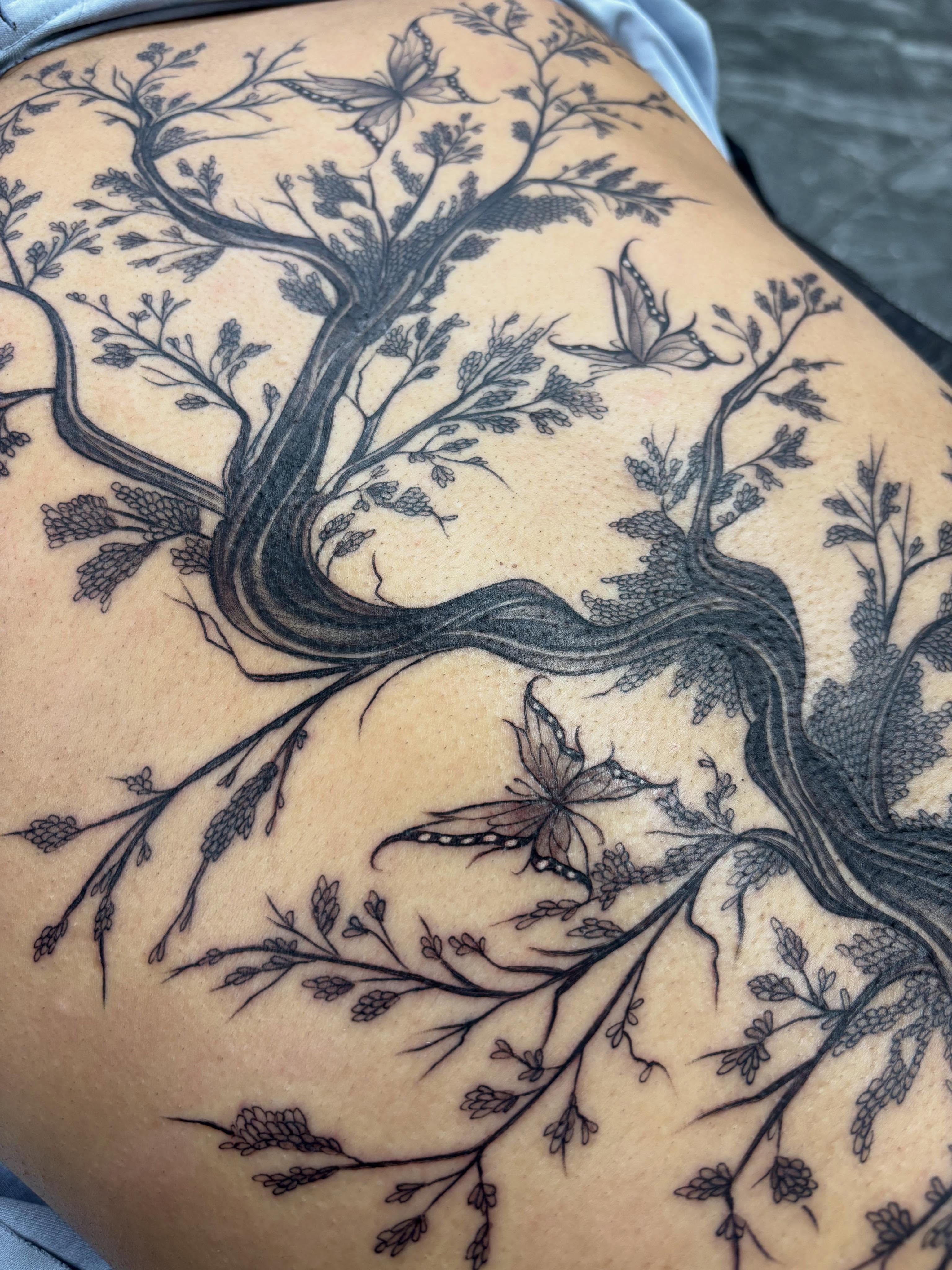 Tree with butterflies black and grey tattoo on the thigh by Jennifer Flores