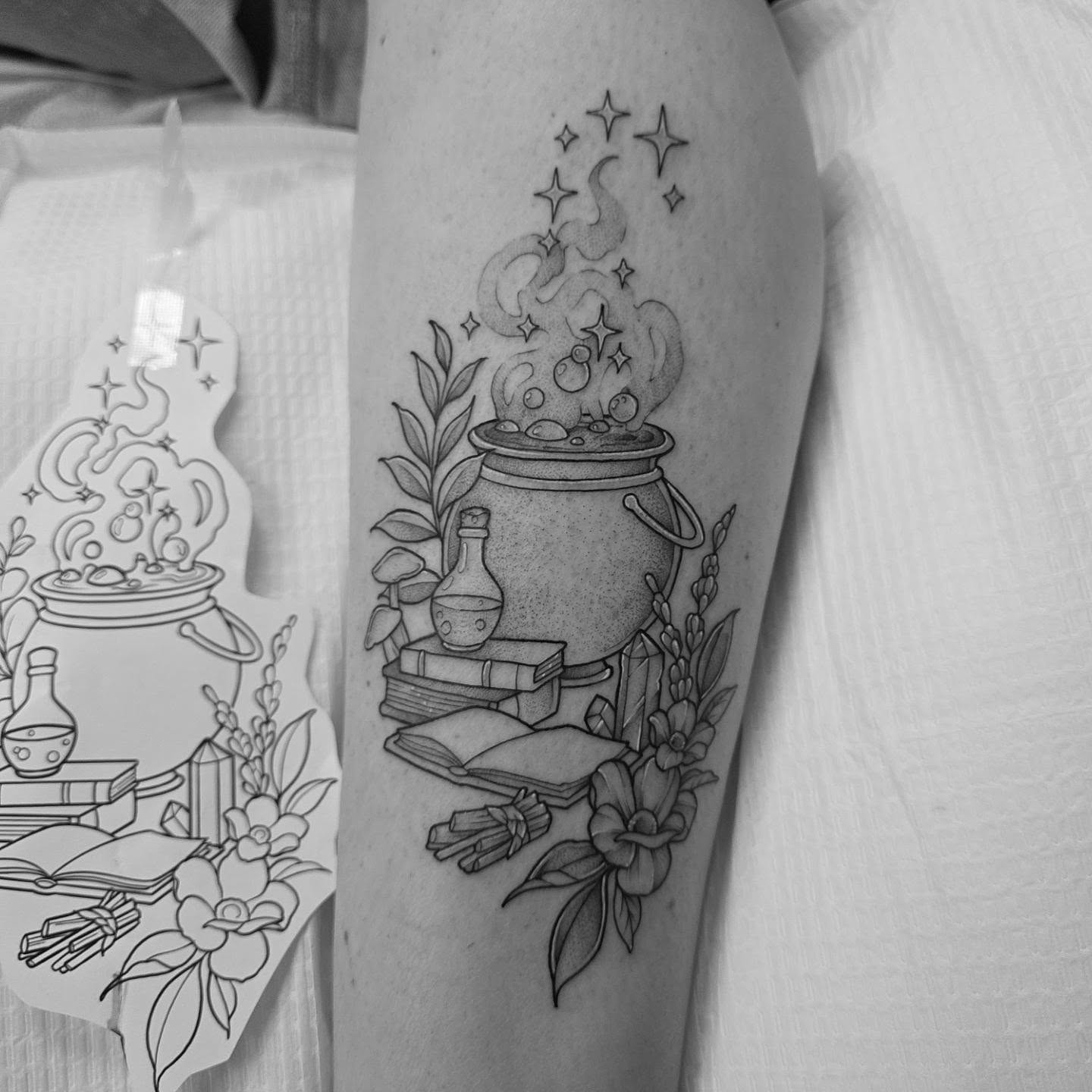 Cauldron and magical elements black and grey tattoo on the forearm by Dani Bond