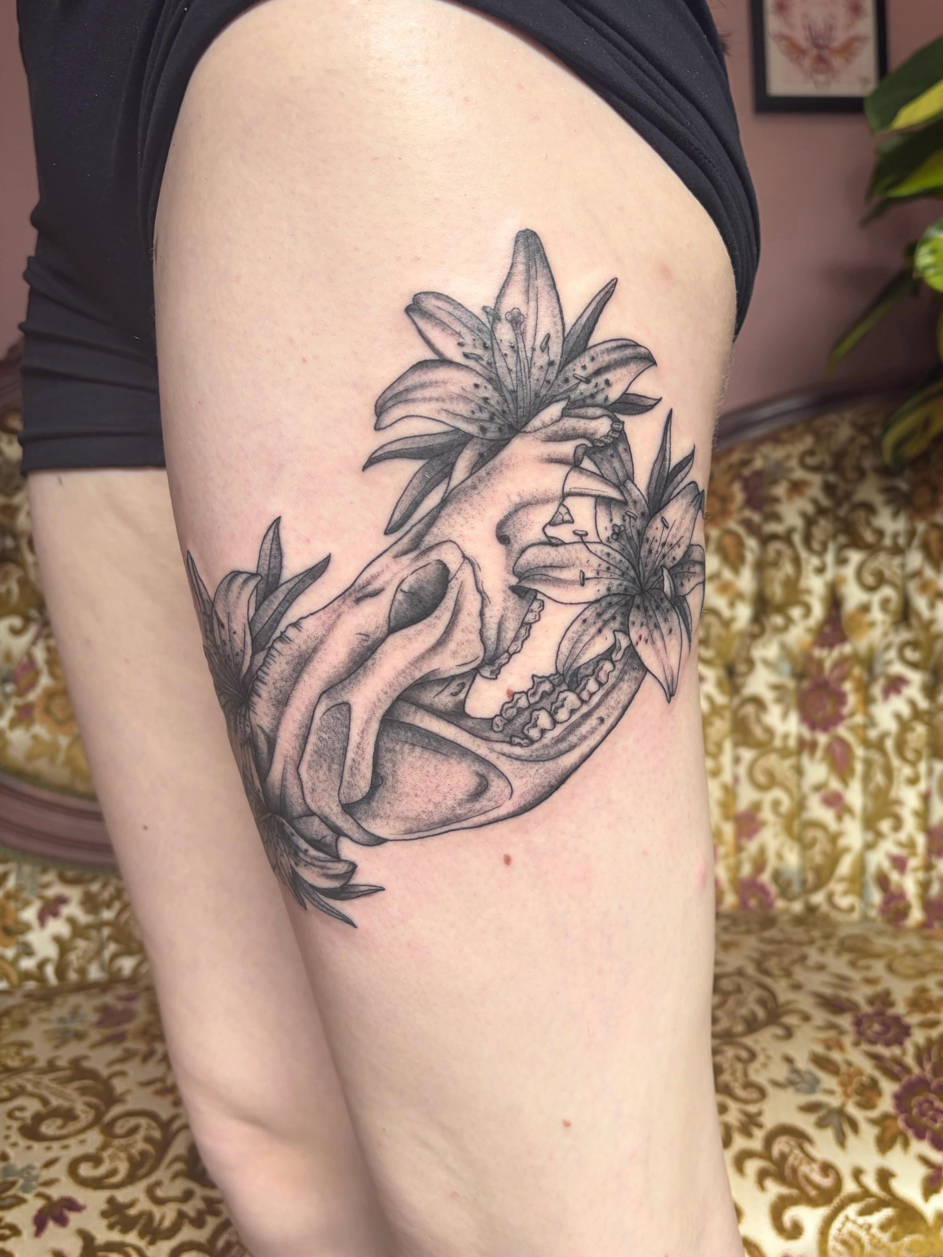 Skull and lilies realism tattoo on the thigh by Mary Hannah Sosdian