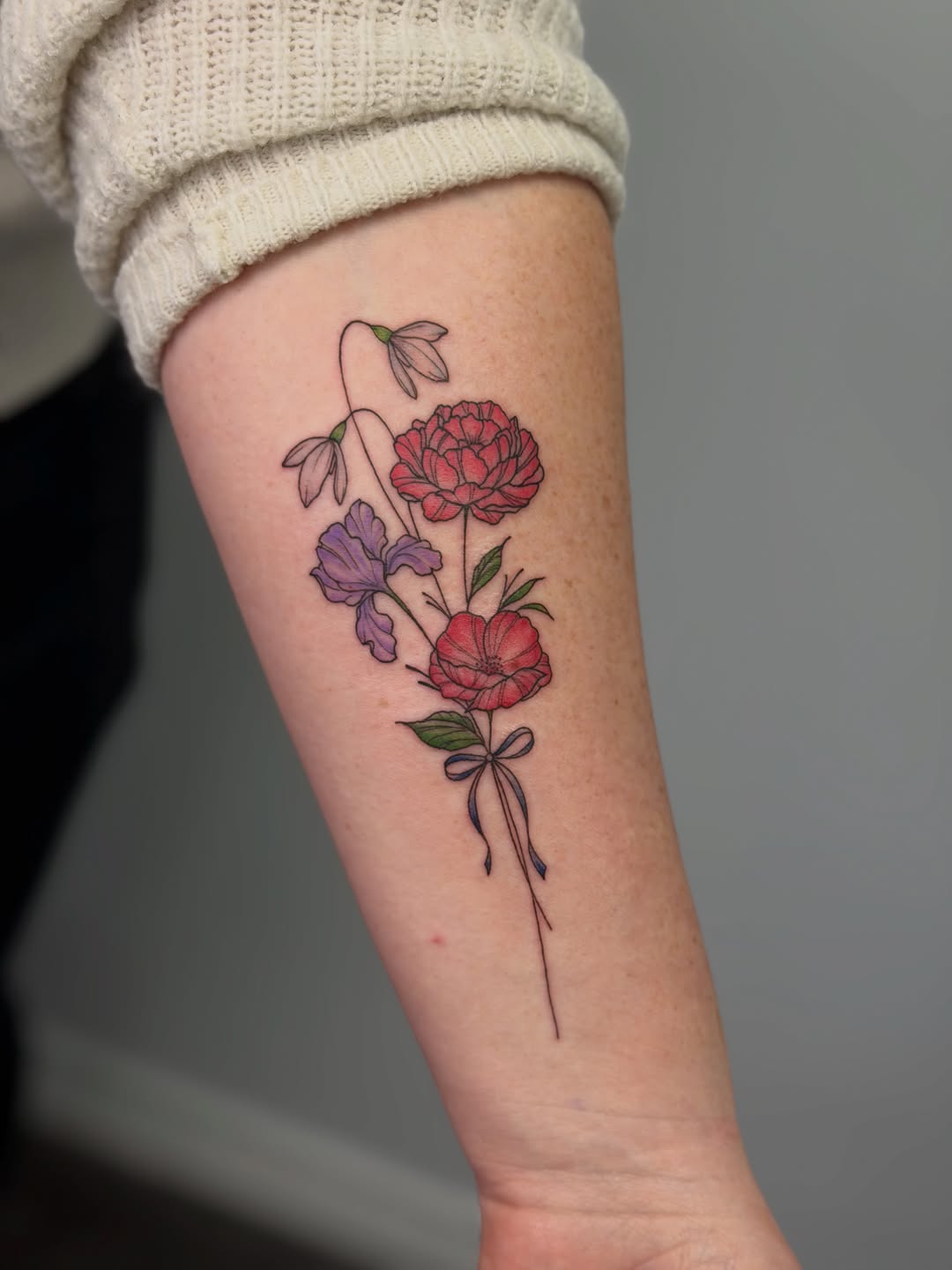 Flower bouquet with ribbon watercolor tattoo on the forearm by Mandy Kaur