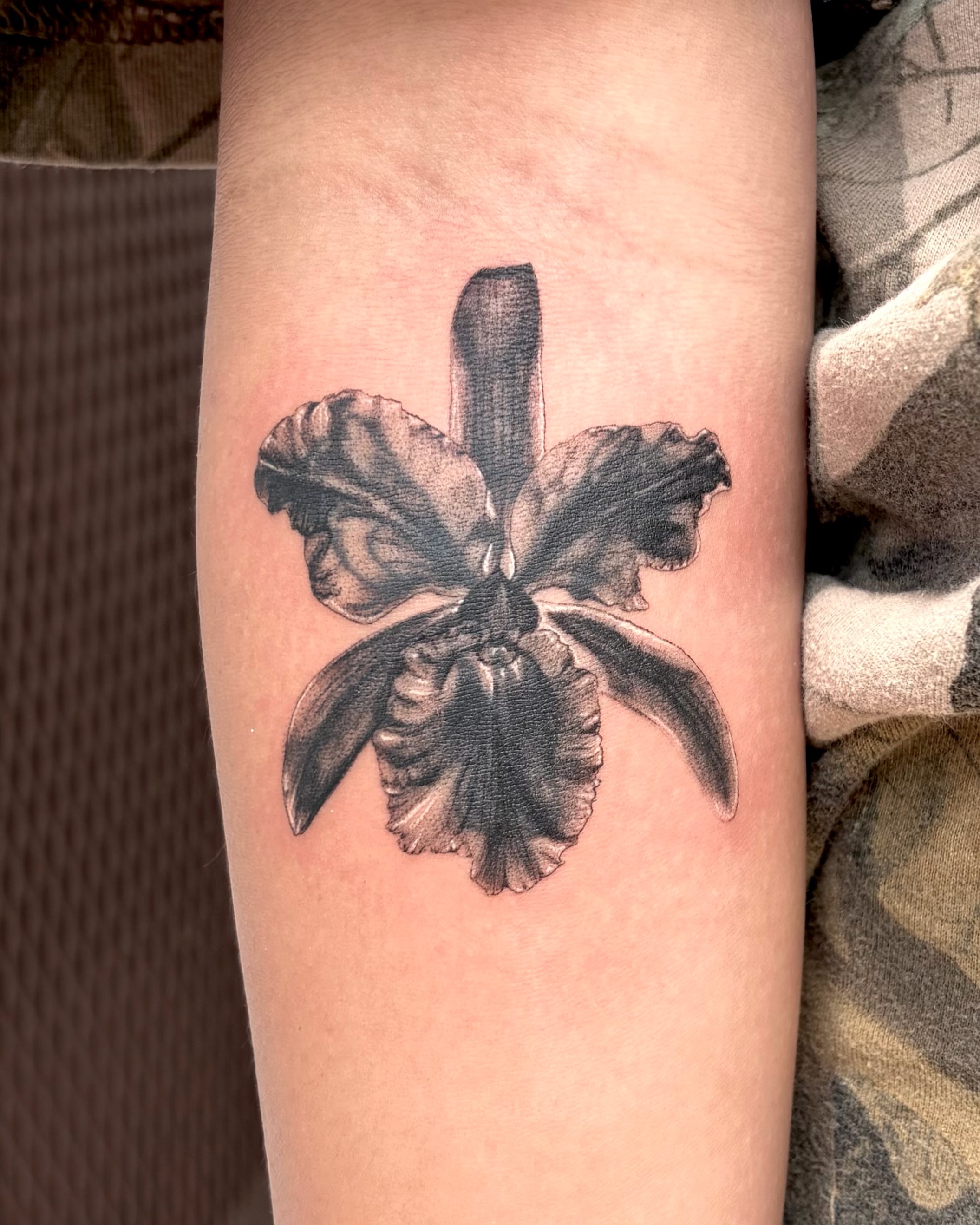 Orchid black and grey tattoo on the forearm by Kylah Amin Tattoo
