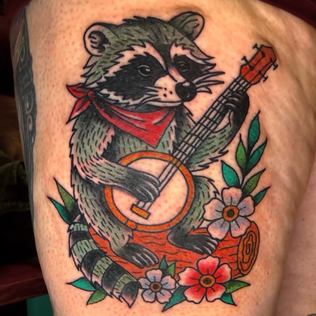 Raccoon playing banjo American traditional tattoo on the thigh by π Erin Stephens π€