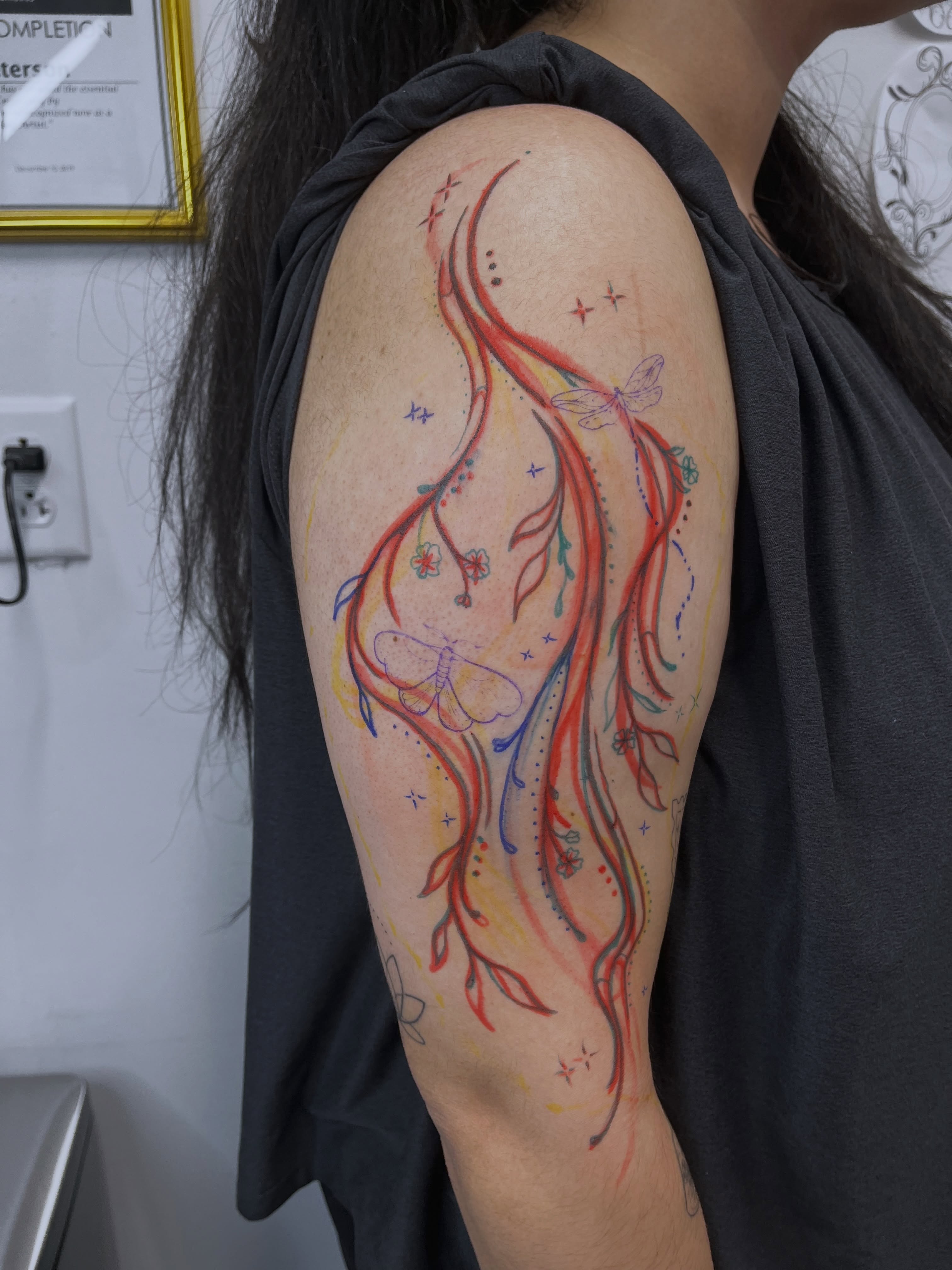 Watercolor swirls and butterflies watercolor tattoo on the upper arm by Sid