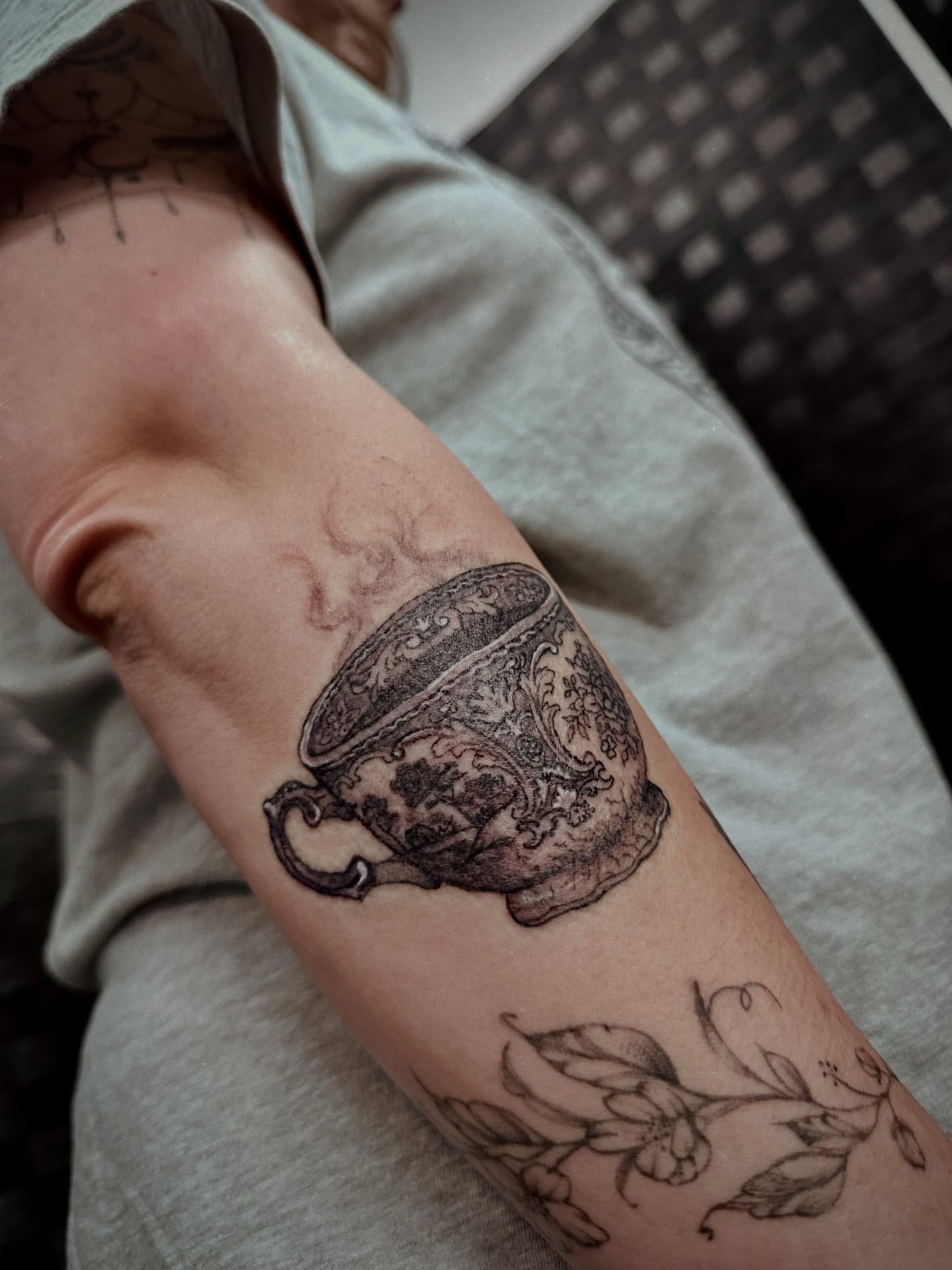 Teacup and floral design black and grey tattoo on the forearm by Marlyn “Lala”