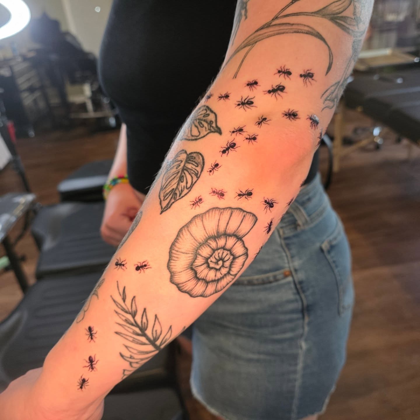 Ants and snail shell black and grey tattoo on the forearm by Maggie