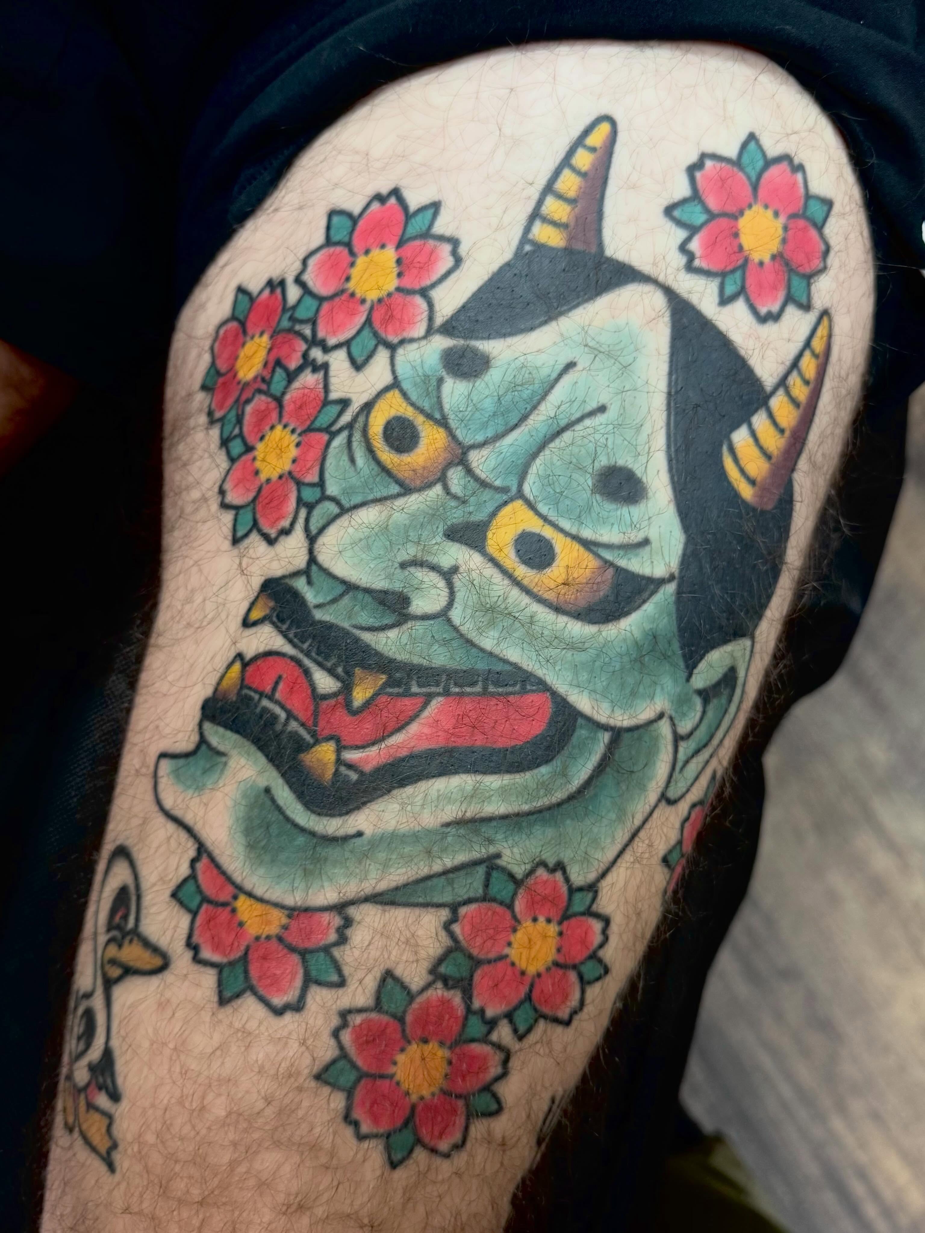 Demon mask with flowers American traditional tattoo on the forearm by Landon Lewis