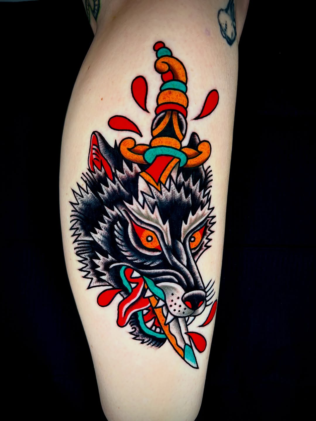 Wolf head with dagger American traditional tattoo on the thigh by Alex Muniz
