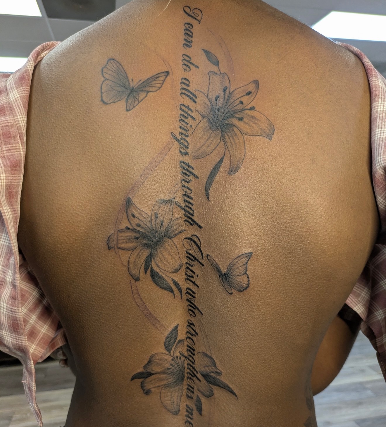 Religious quote black and grey tattoo on the back by Buddy K.