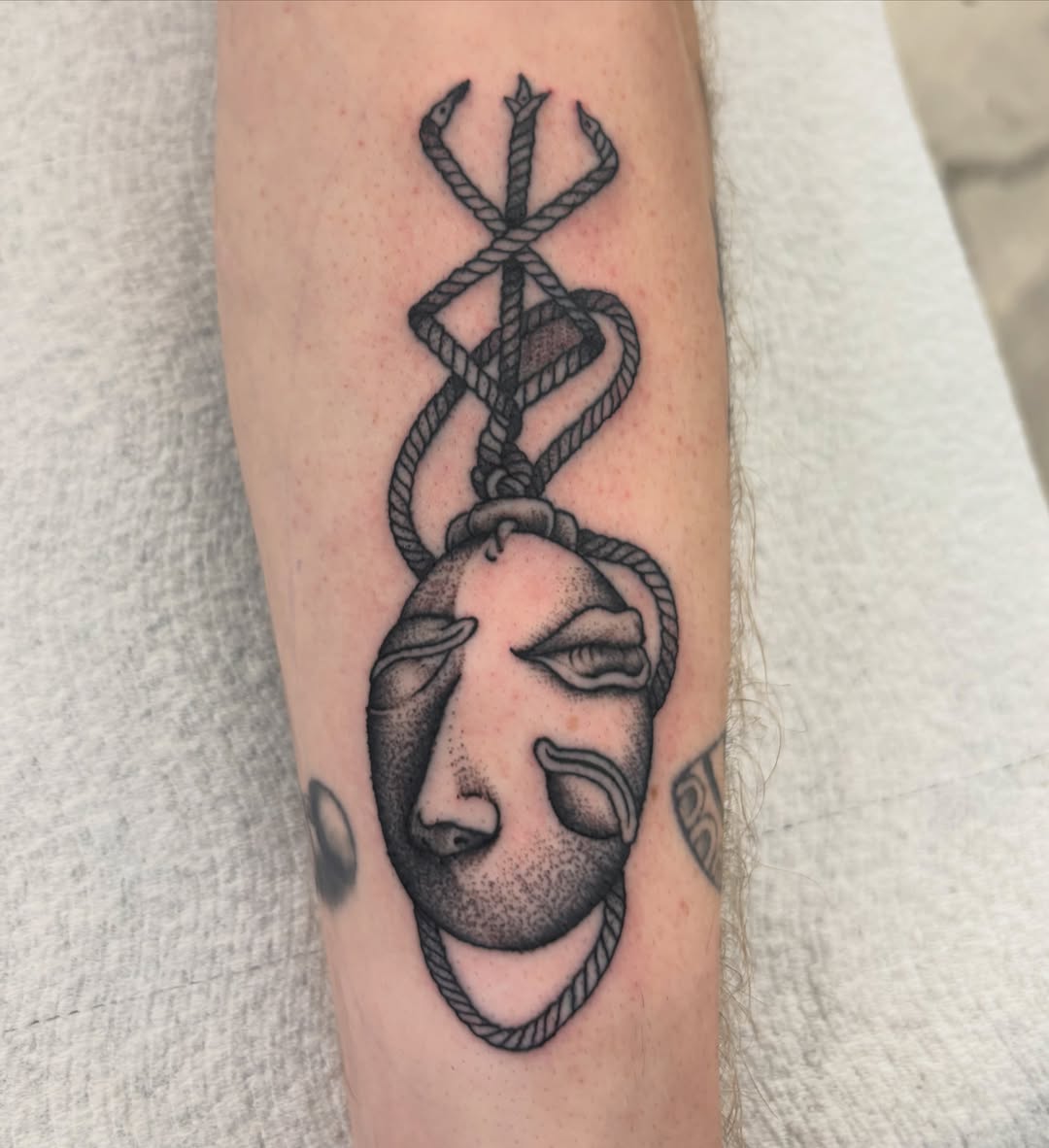 Mask with rope dotwork tattoo on the forearm by Miklo Montoya
