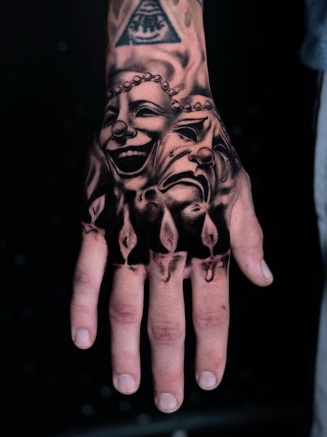 Comedy and tragedy masks realism tattoo on the hand by Charlotte Tattoo Artist