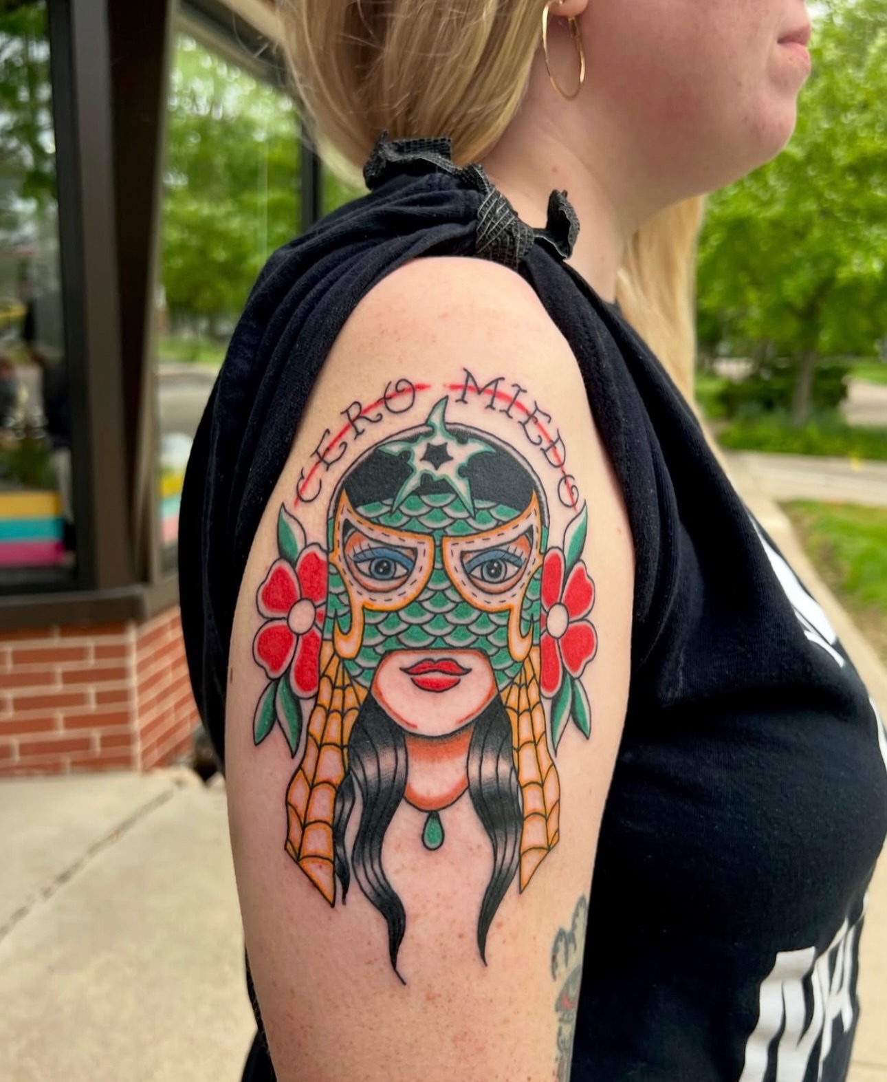 Woman wearing mask American traditional tattoo on the shoulder by Dustie Pitstick