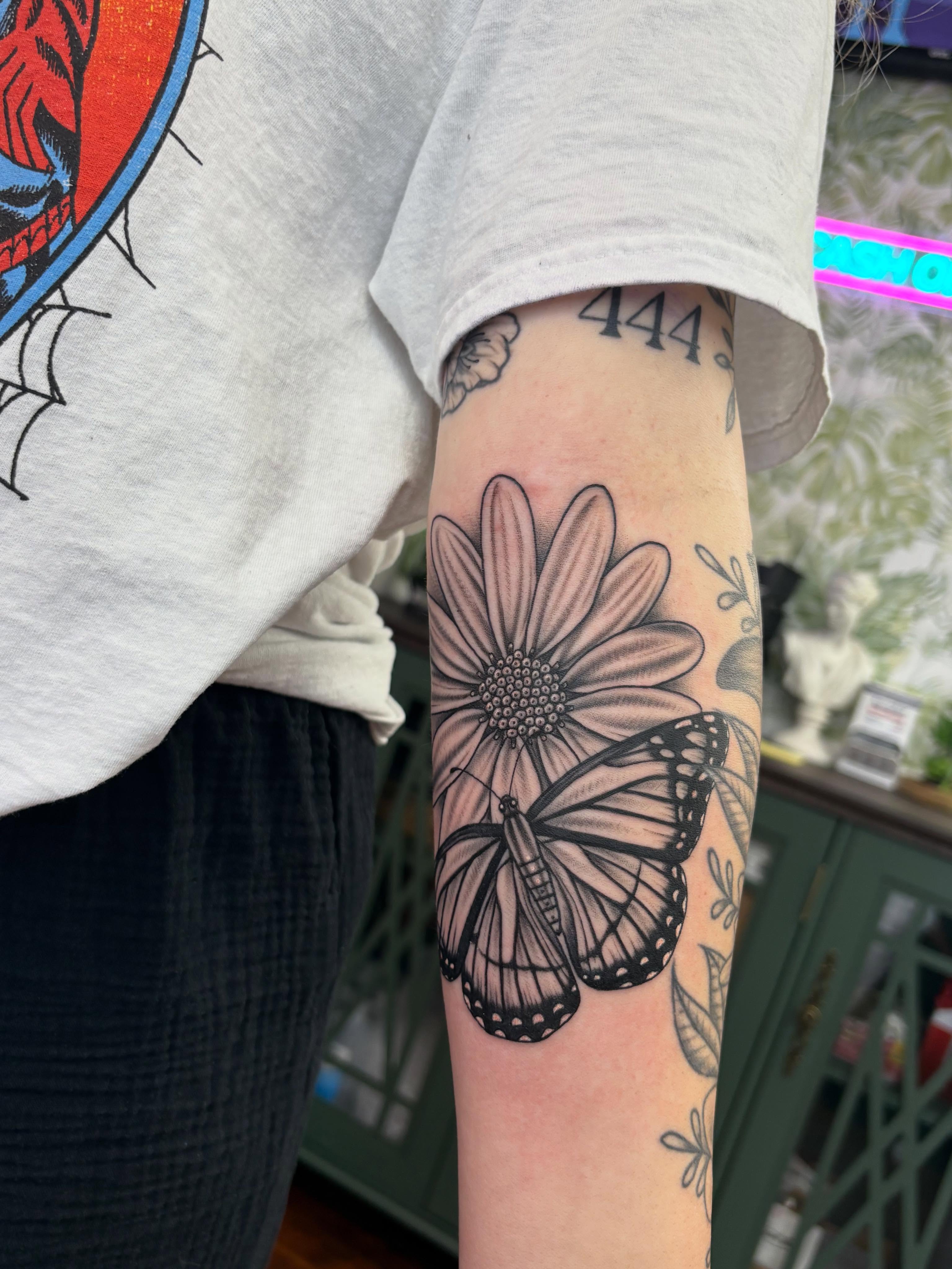 Butterfly and flower realism tattoo on the forearm by Skye California