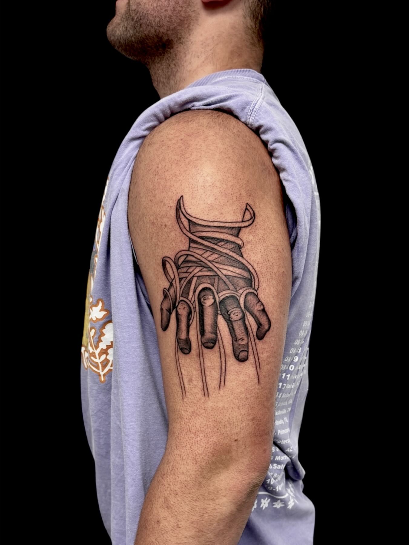 Hand with rope realism tattoo on the upper arm by Cody Glenn