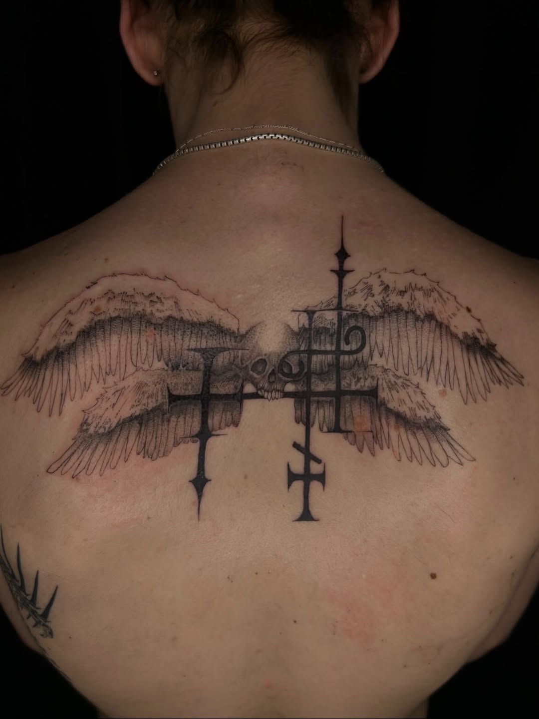 Wings with skull and crosses cyber sigilism tattoo on the back by Jadin Nichols