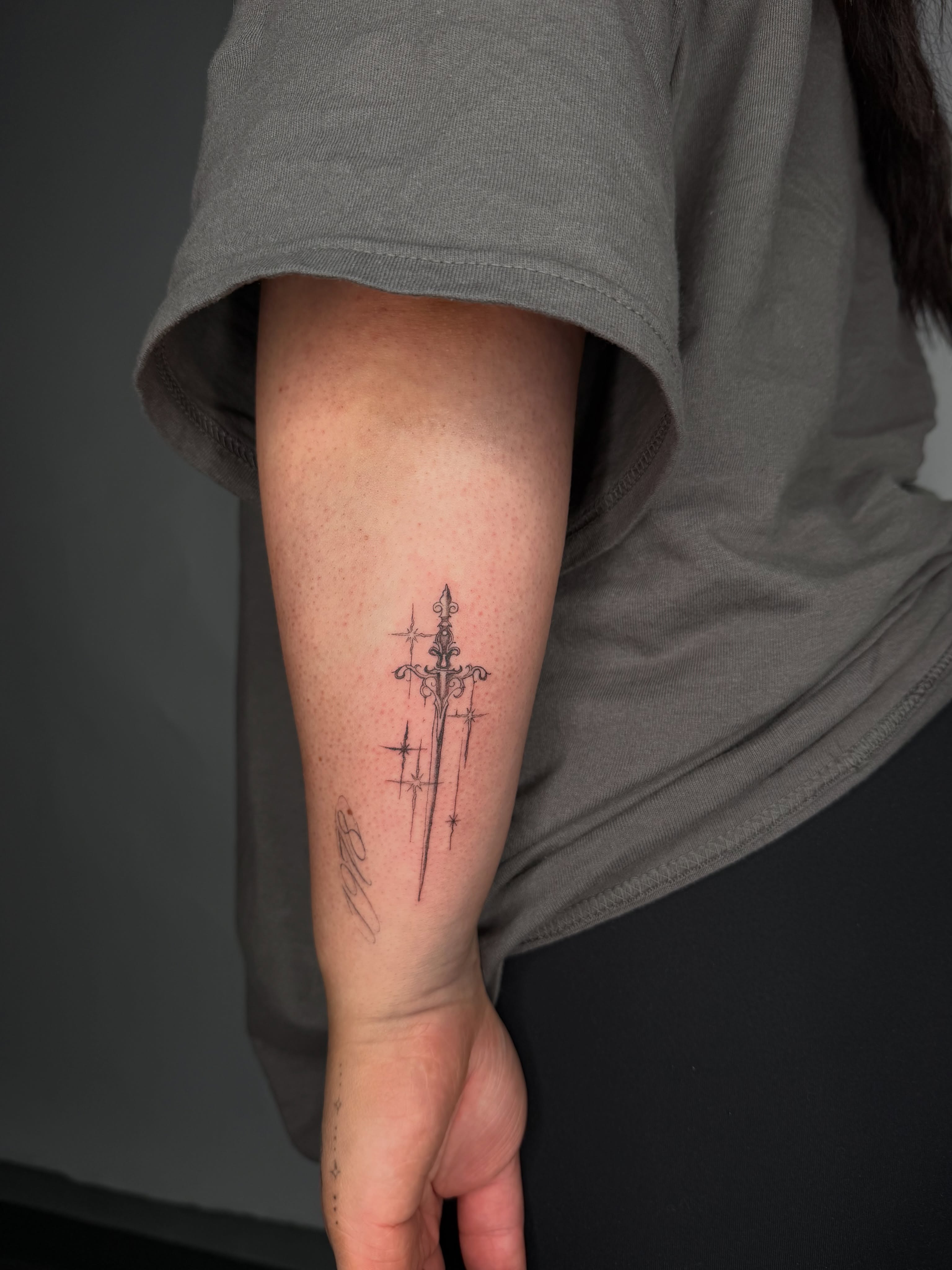 Sword and stars black and grey tattoo on the forearm by DFW Fineline Tattoo Artist