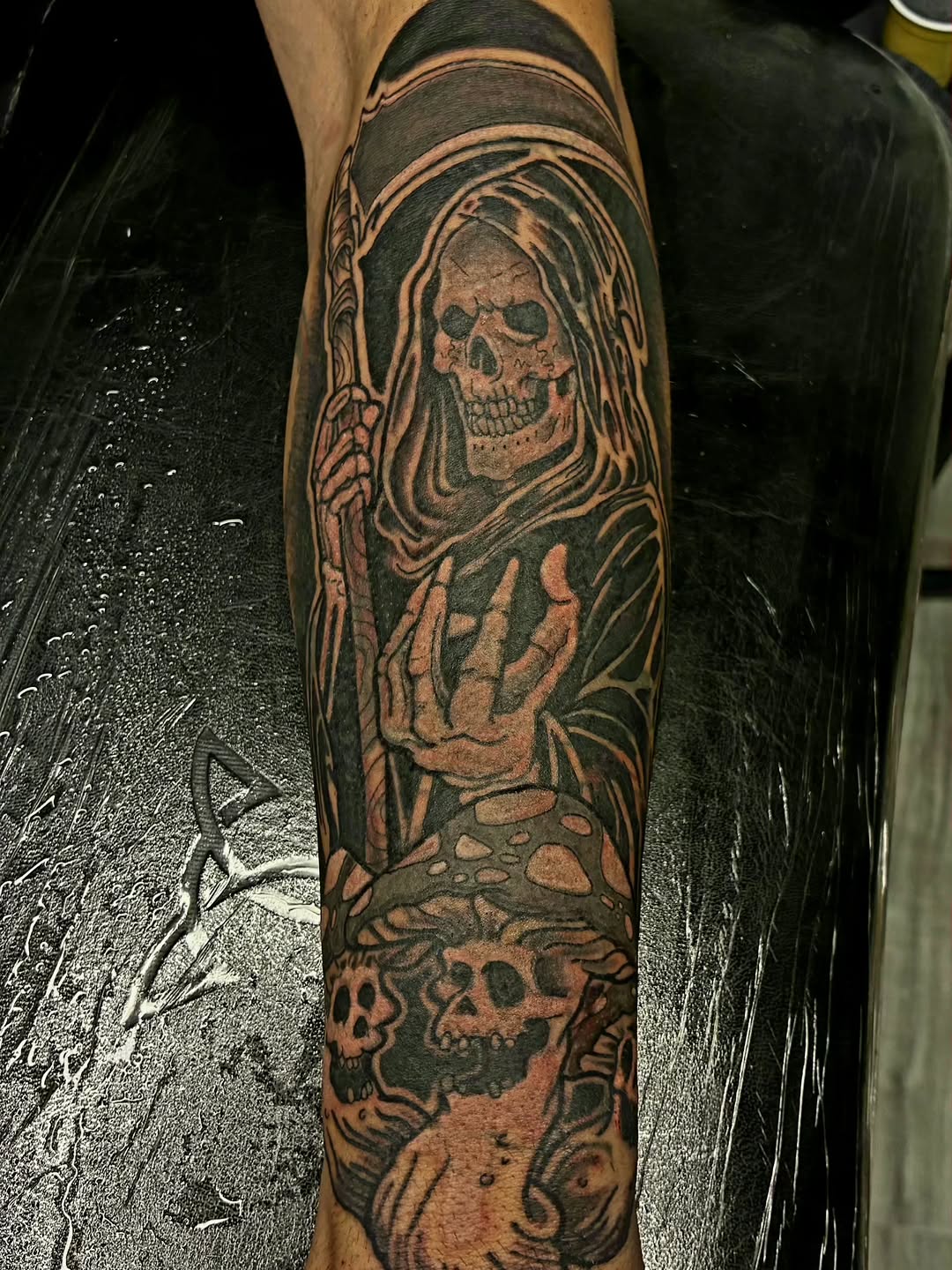 Grim reaper with skulls and mushroom dark art tattoo on the forearm by Captain Michael Devious