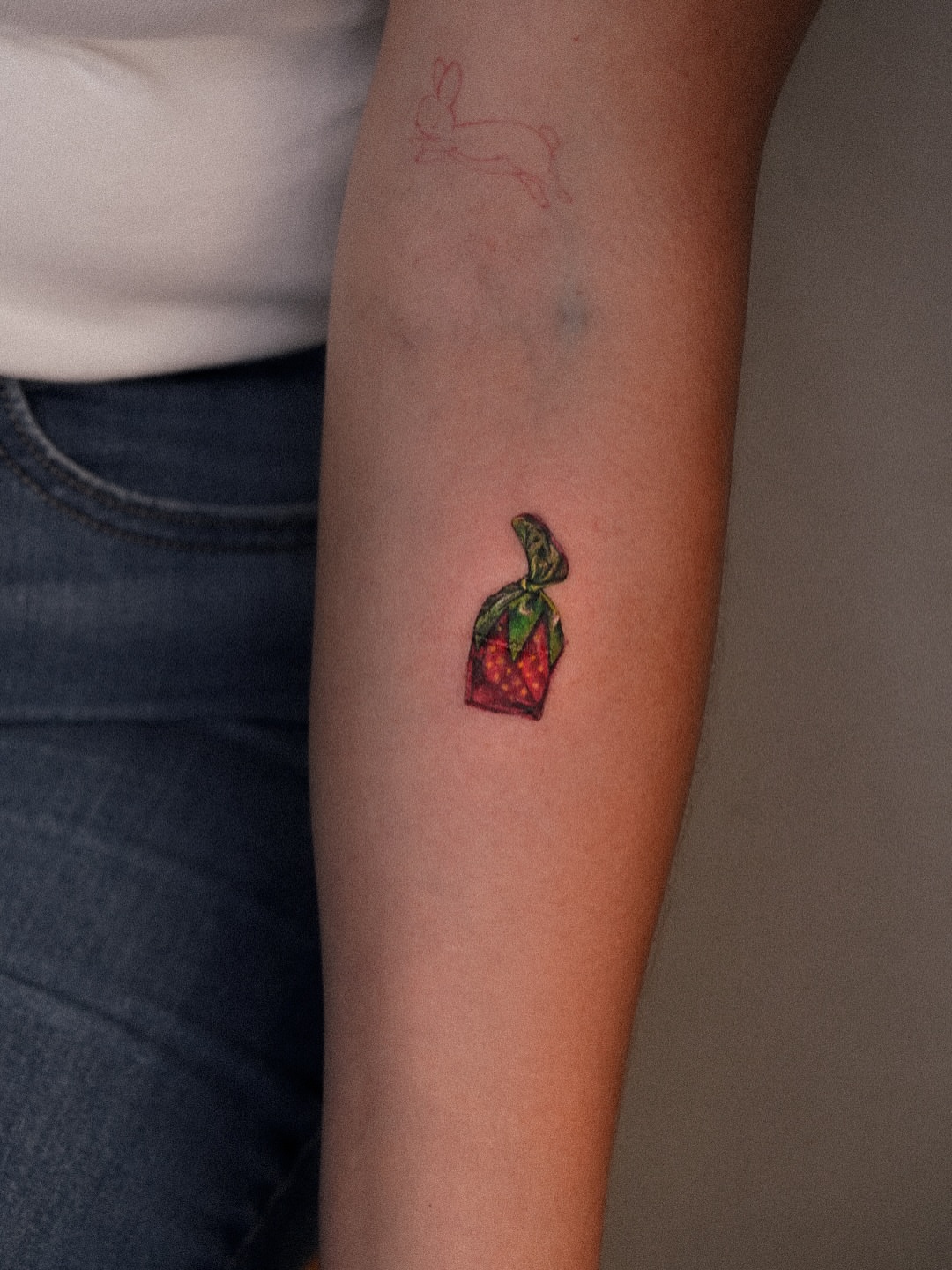 Strawberry in bag realism tattoo on the forearm by Joy Christiana