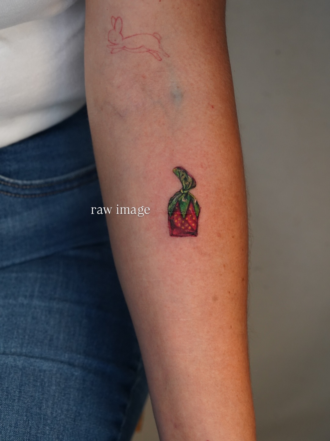 Strawberry in a box watercolor tattoo on the forearm by Joy Christiana