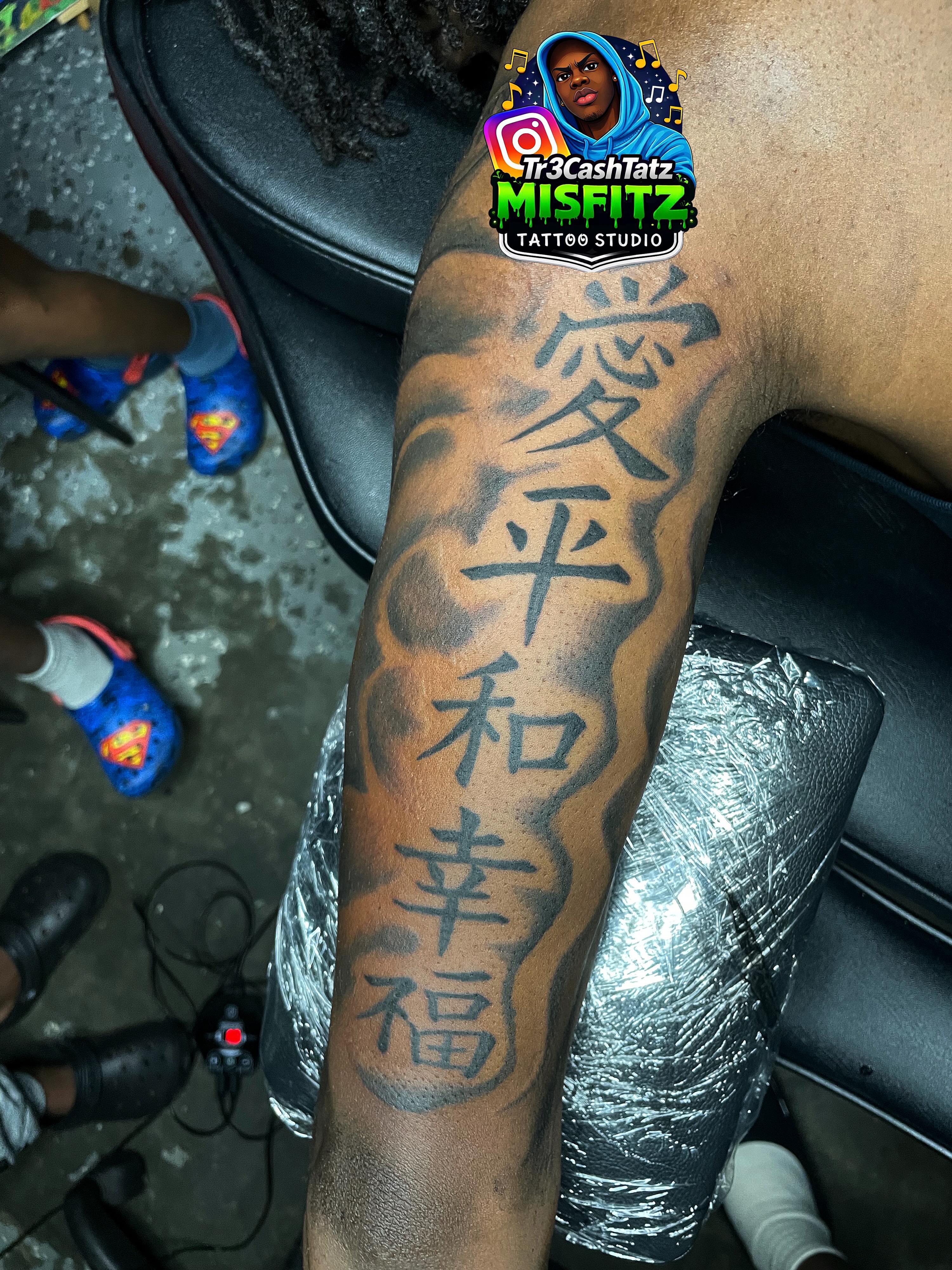 Kanji characters black and grey tattoo on the upper arm by TreCashTats💉🩸 MisfitzTattooStudio
