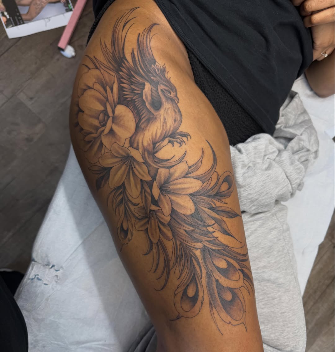 Peacock and flowers black and grey tattoo on the thigh by Jordan Clifford