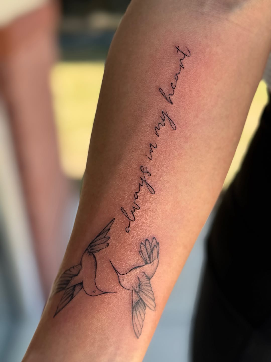 Hummingbirds and script lettering lettering tattoo on the forearm by Emily Velletta, Huntersville, North Carolina