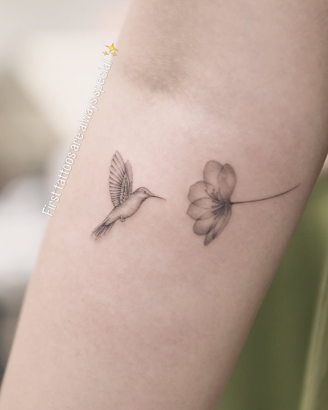 Hummingbird and flower watercolor tattoo on the forearm by Joey