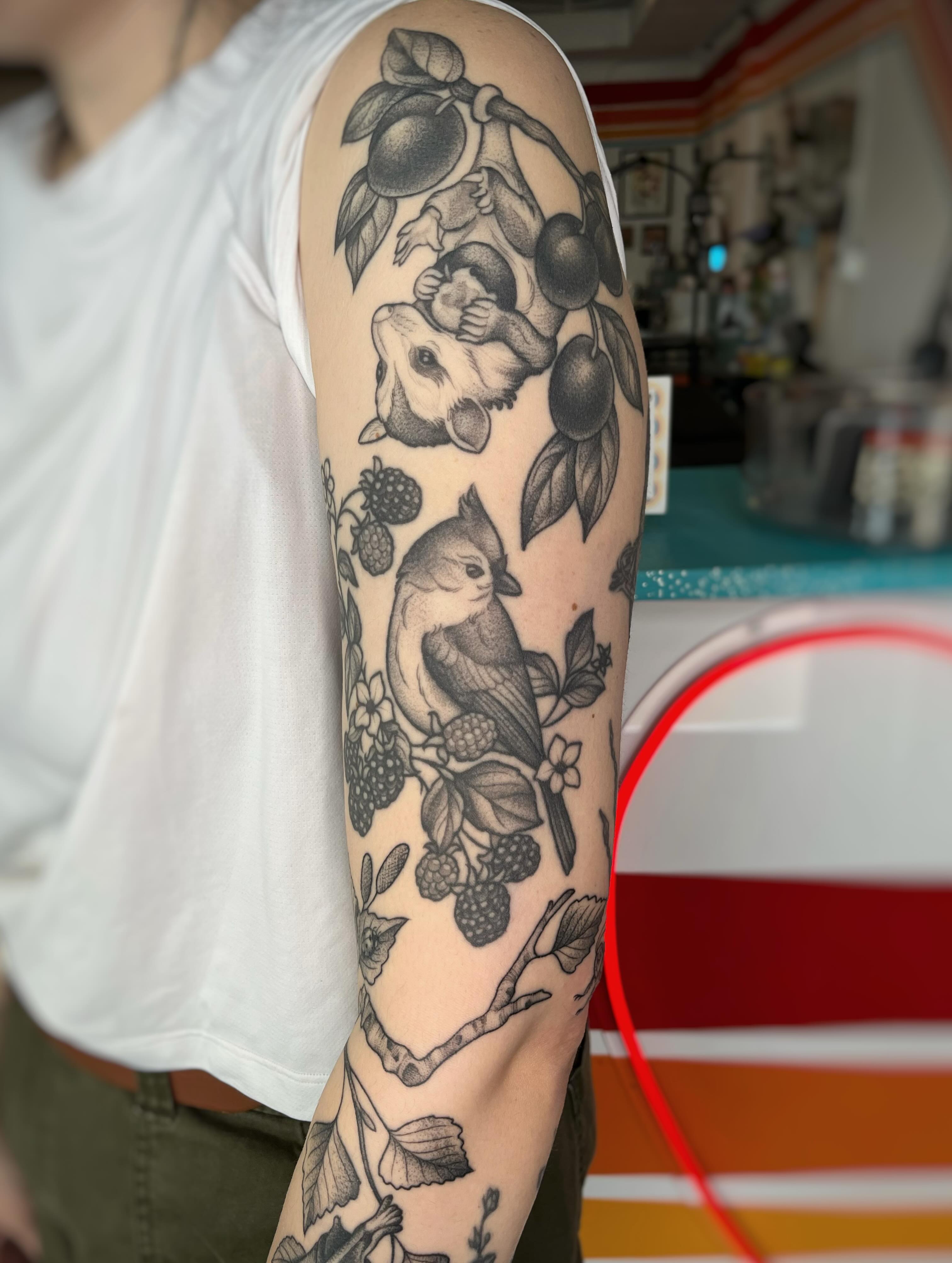 Fruit and bird black and grey tattoo on the forearm by Emi Collison
