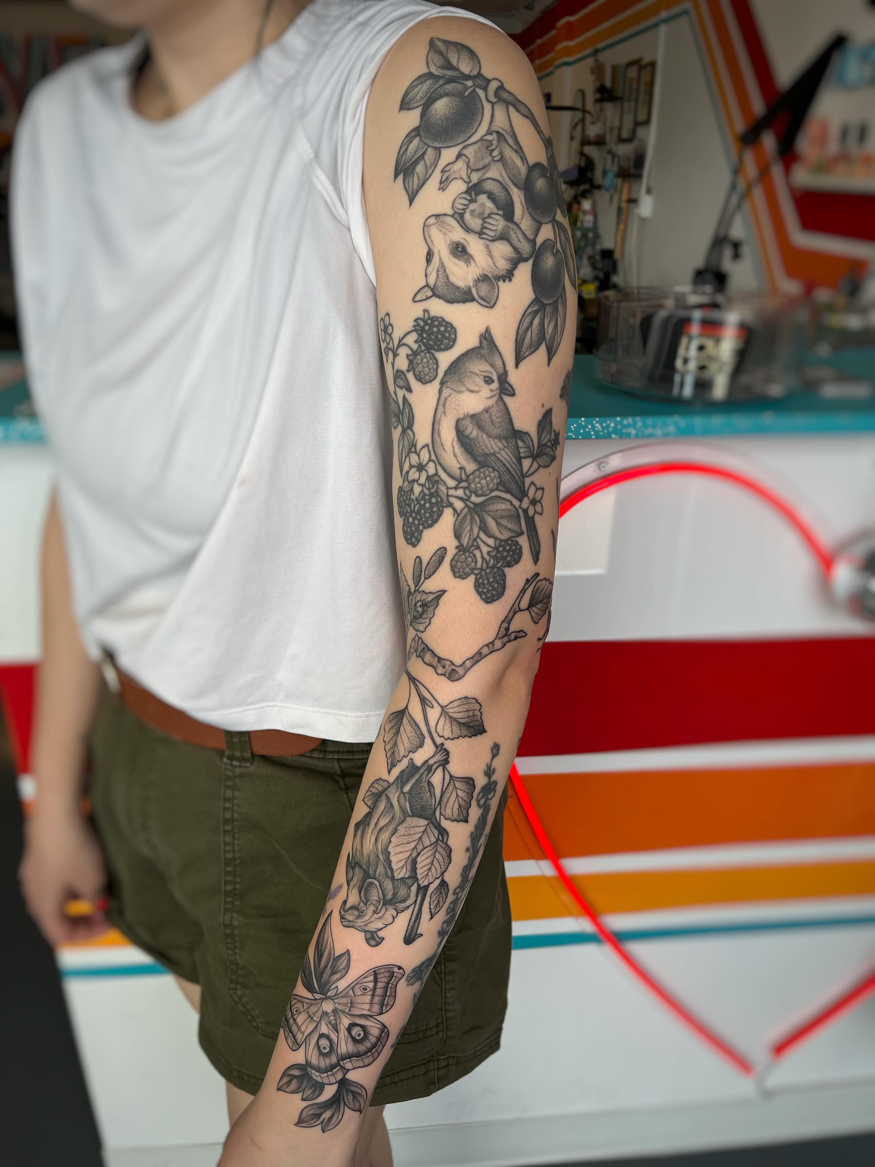 Bird and floral realism tattoo on the forearm by Emi Collison