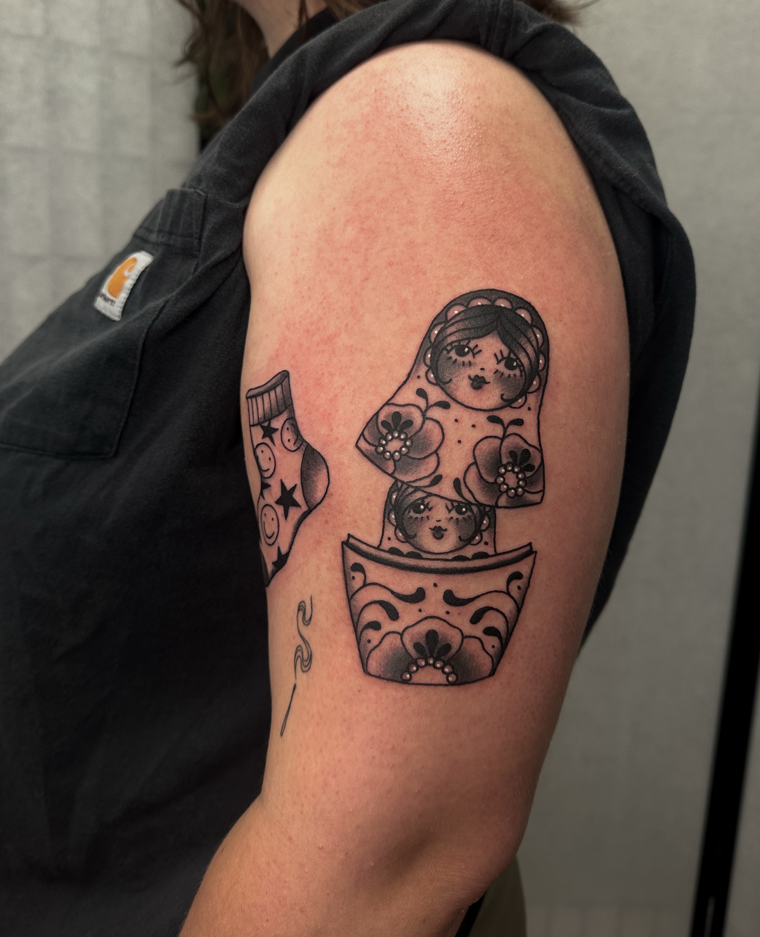 Matryoshka doll black and grey tattoo on the shoulder by Hannah Eddy