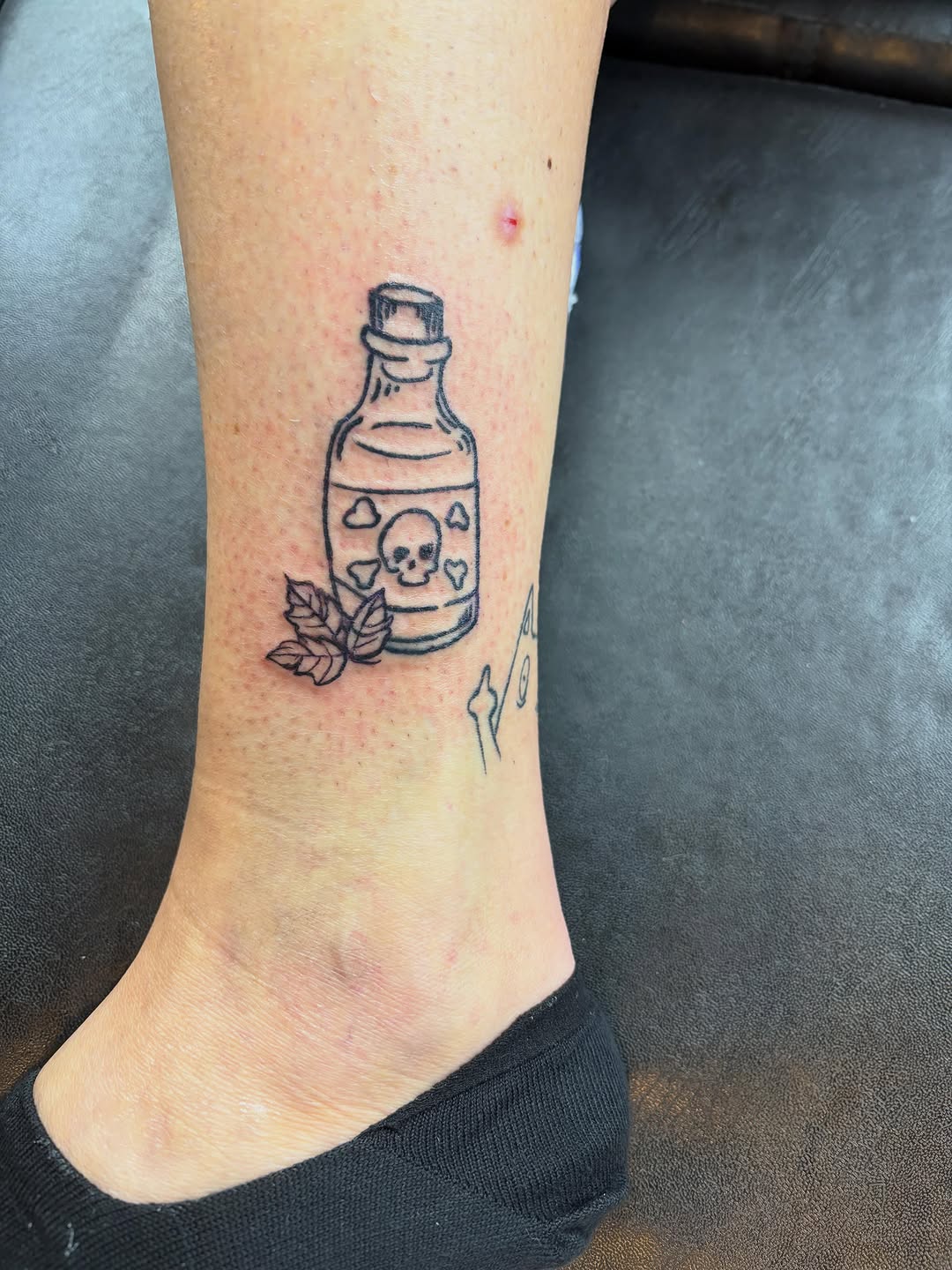 Poison bottle with skull dark art tattoo on the calf by Madison