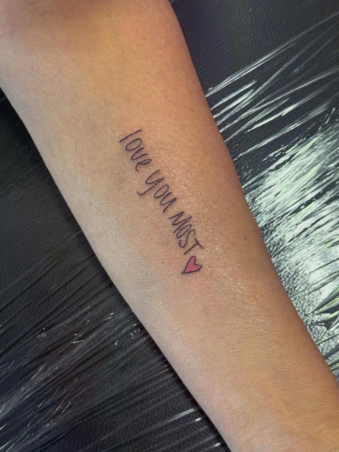 Script lettering with heart lettering tattoo on the forearm by Jay