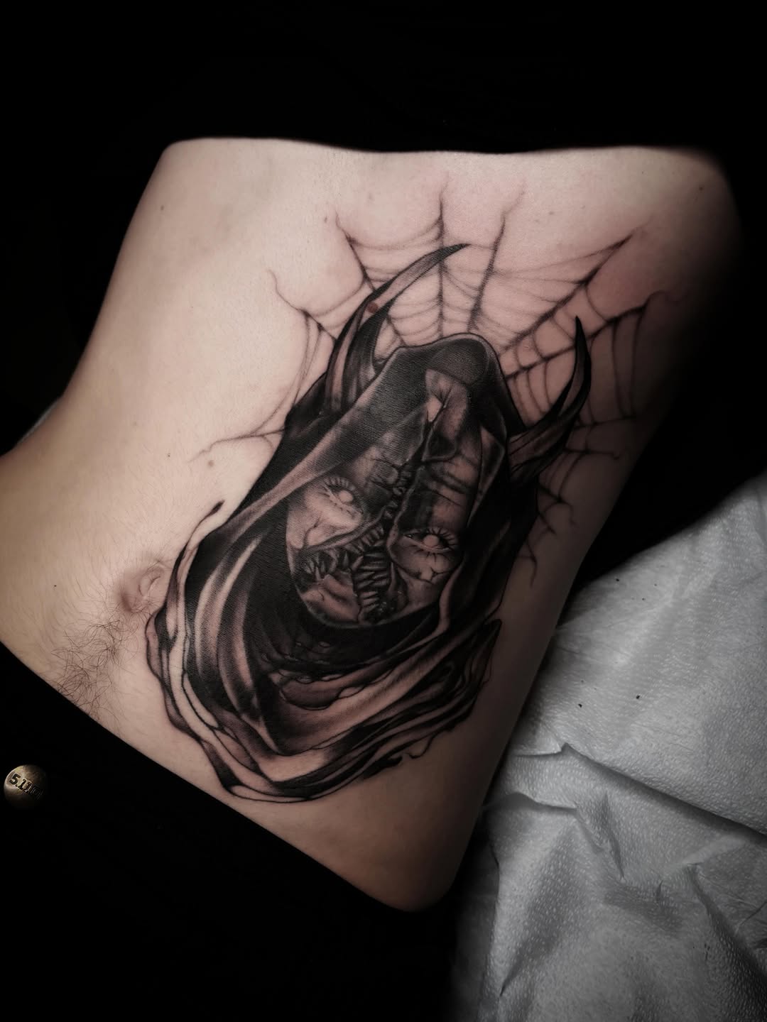 Hooded figure with spiderwebs realism tattoo on the ribs by 𝖎 𝖆𝖒 𝖗𝖔𝖙𝖙𝖎𝖓𝖌 𝖜𝖎𝖙𝖍 𝖞𝖔𝖚