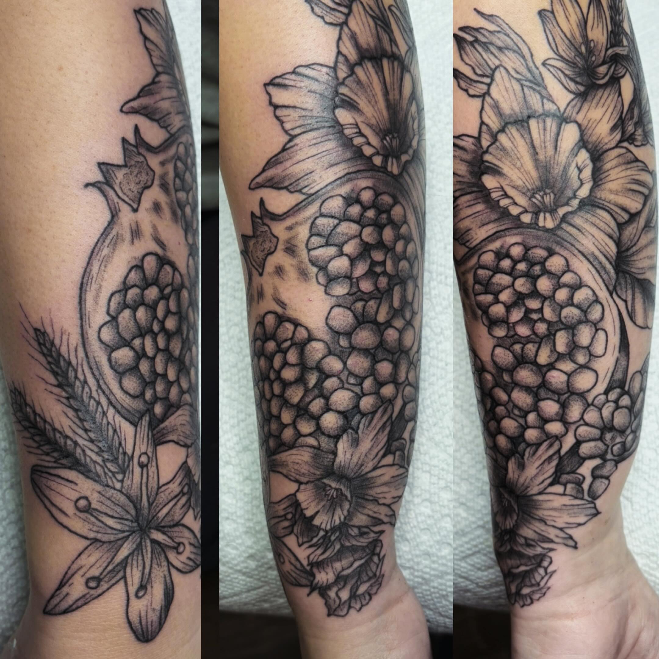 Pomegranate and flowers realism tattoo on the forearm by Mary Hannah Sosdian