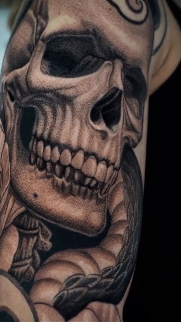 Skull and snake with flowers realism tattoo on the forearm by Enrique Martinez