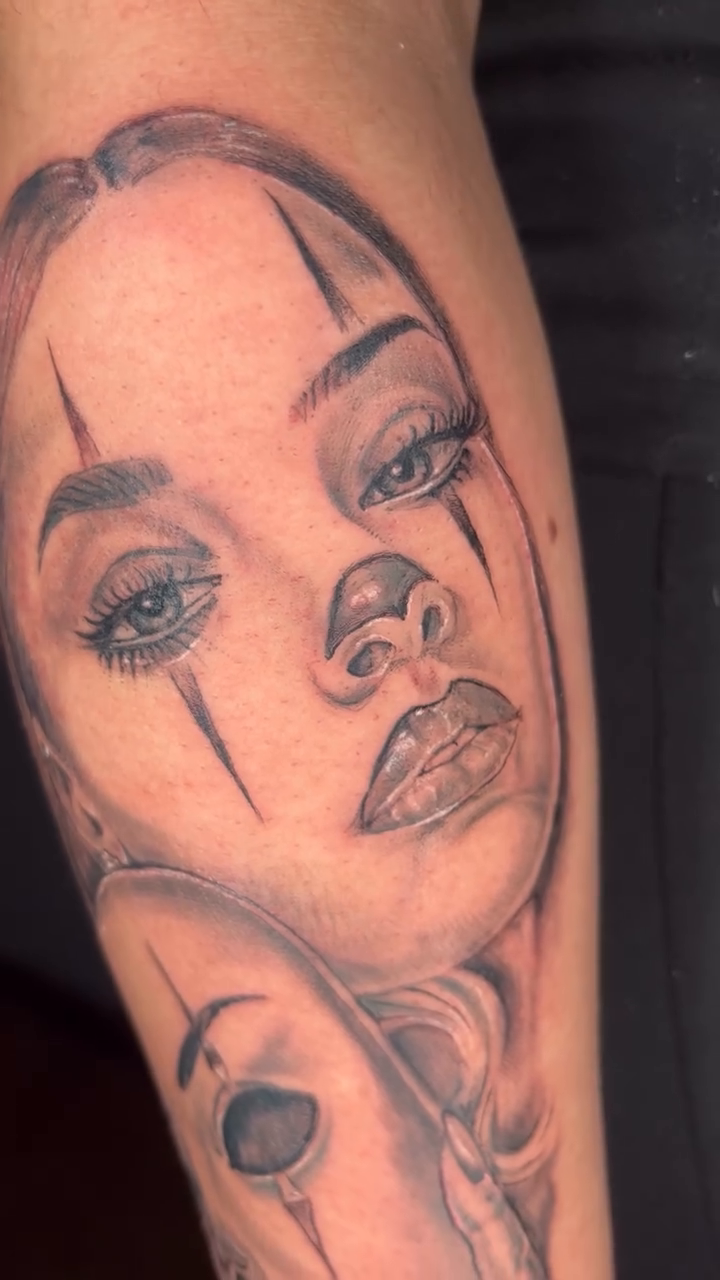 Two faces, one with a mask Chicano tattoo on the forearm by Jakobi