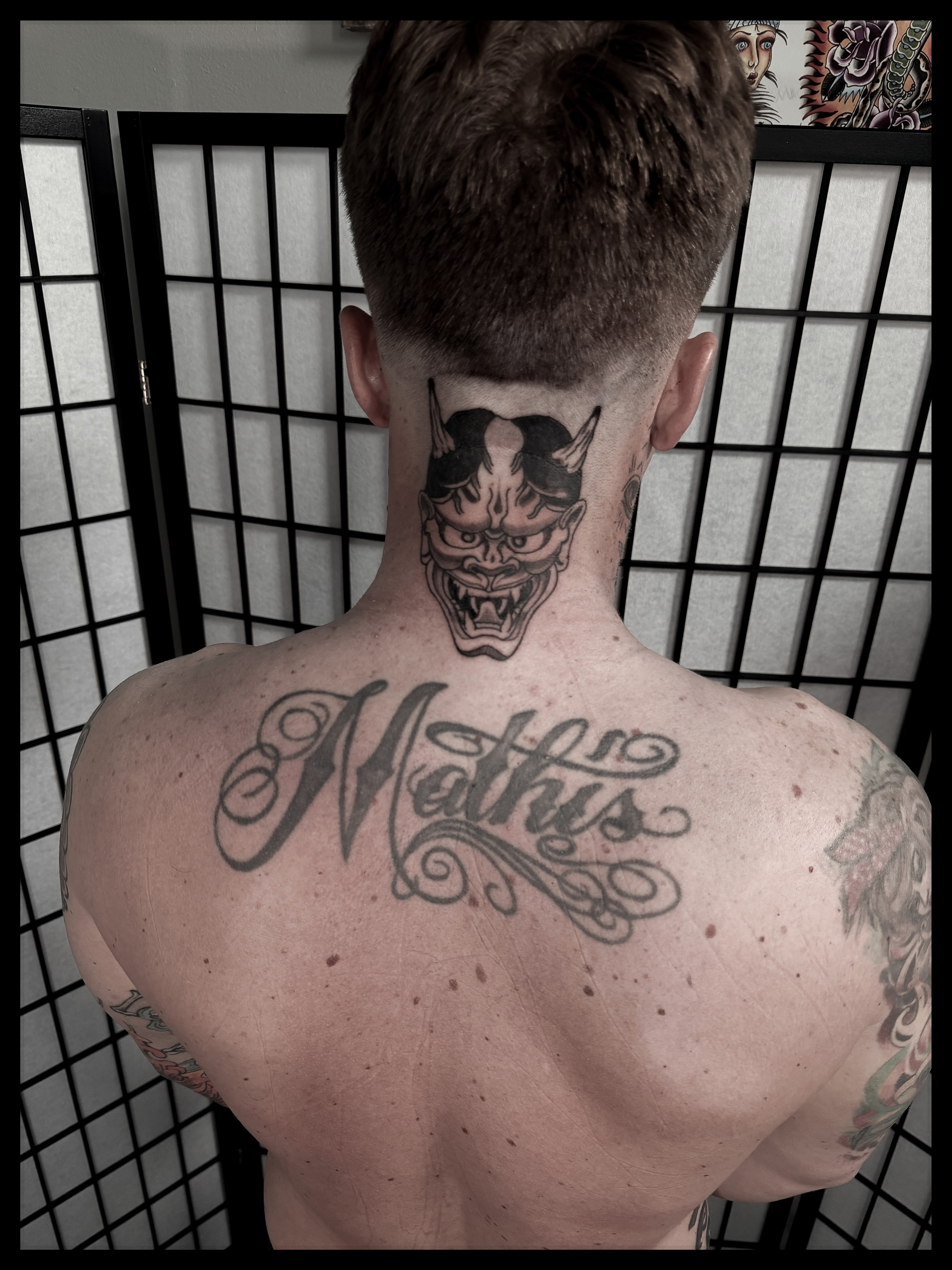 Demon mask black and grey tattoo on the back by Noah Morris