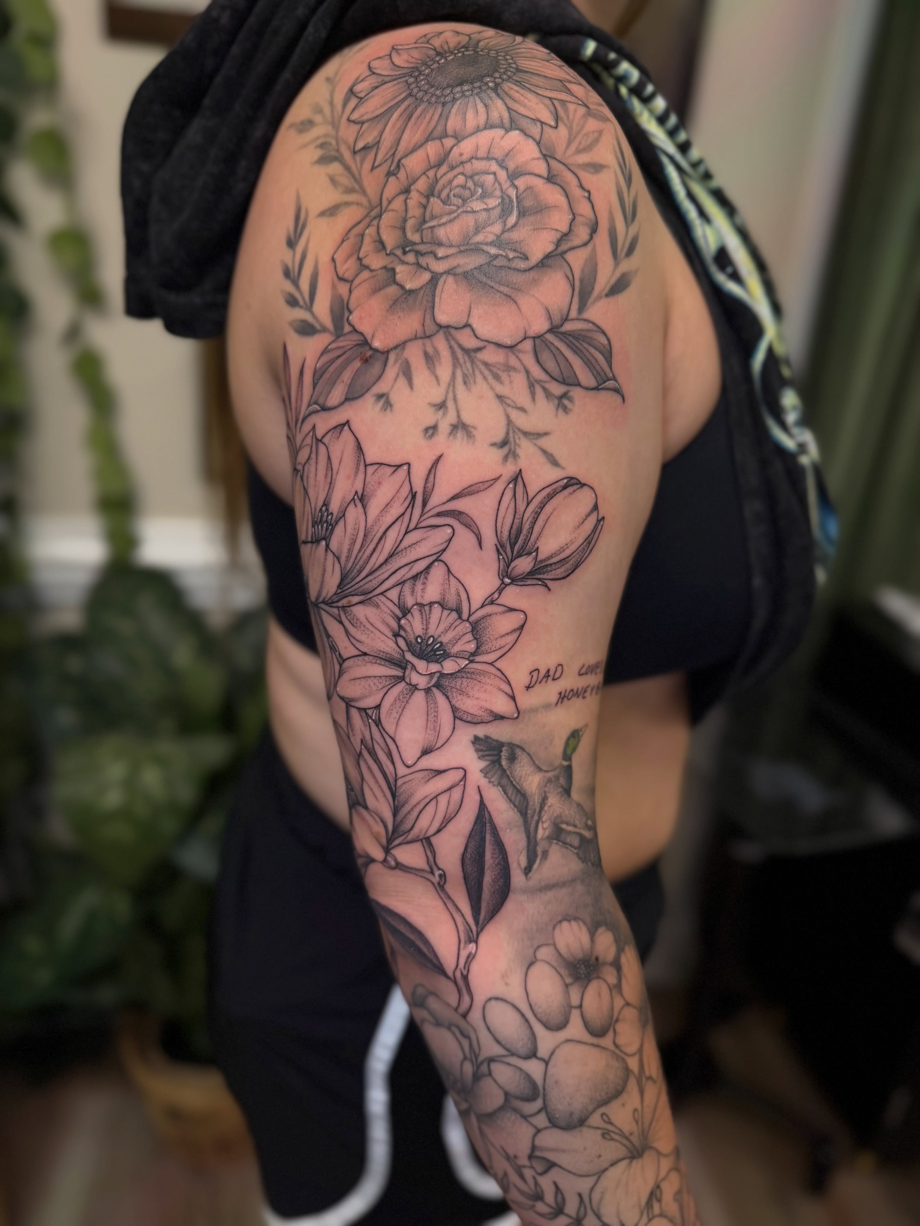 Floral arrangement black and grey tattoo on the upper arm by McKenna