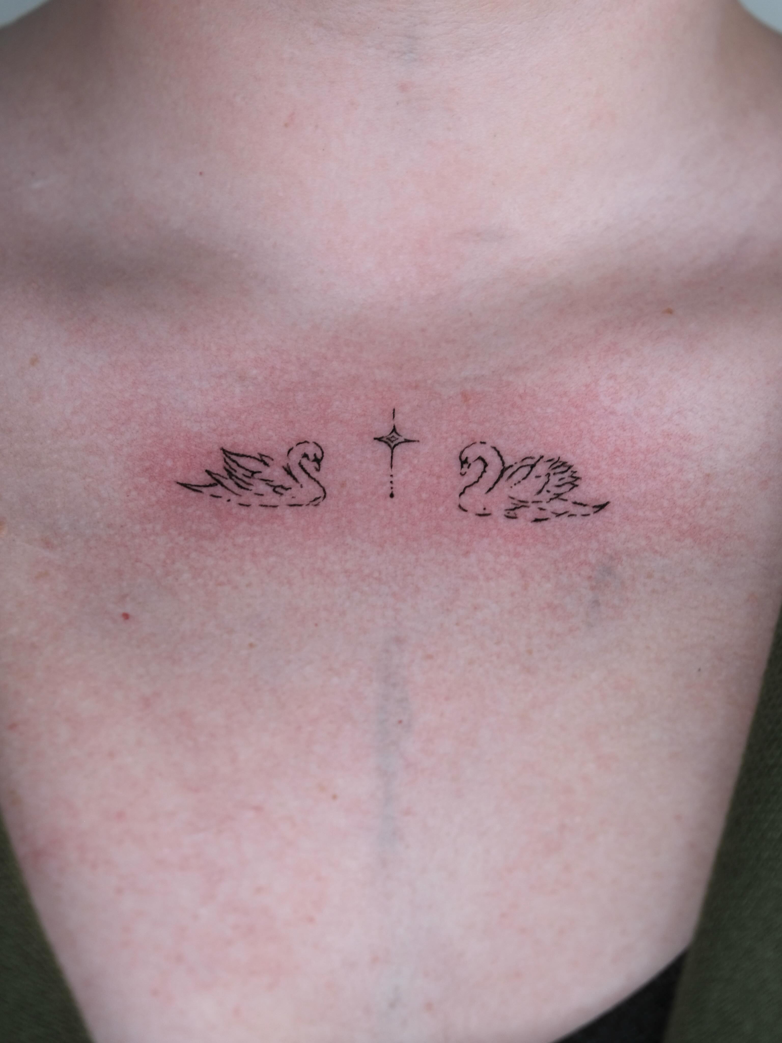 Cross with wings fine line tattoo on the chest by Elana Hites