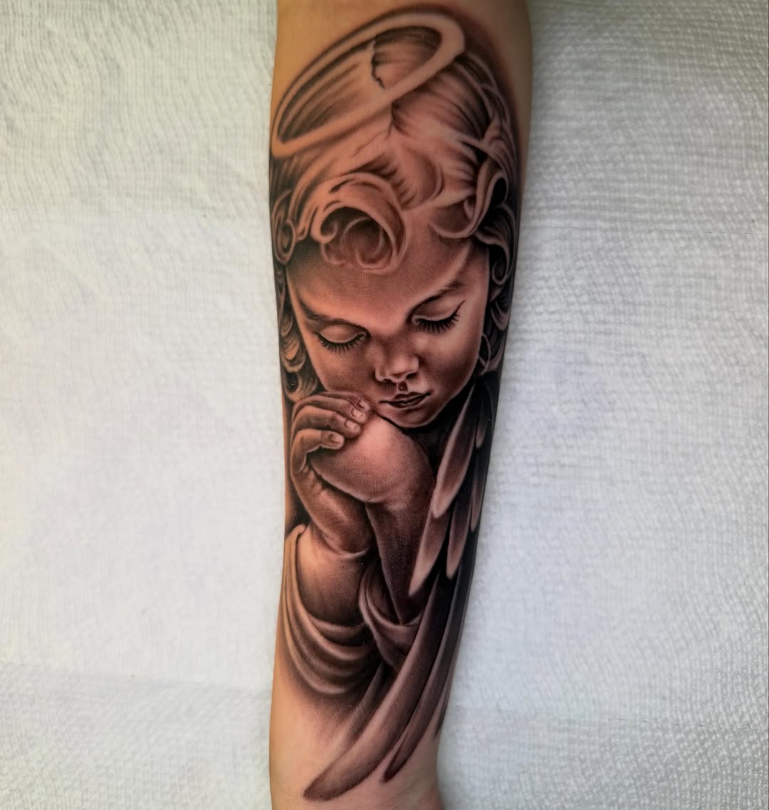 Angel child praying realism tattoo on the forearm by Denver Tattoo Artist