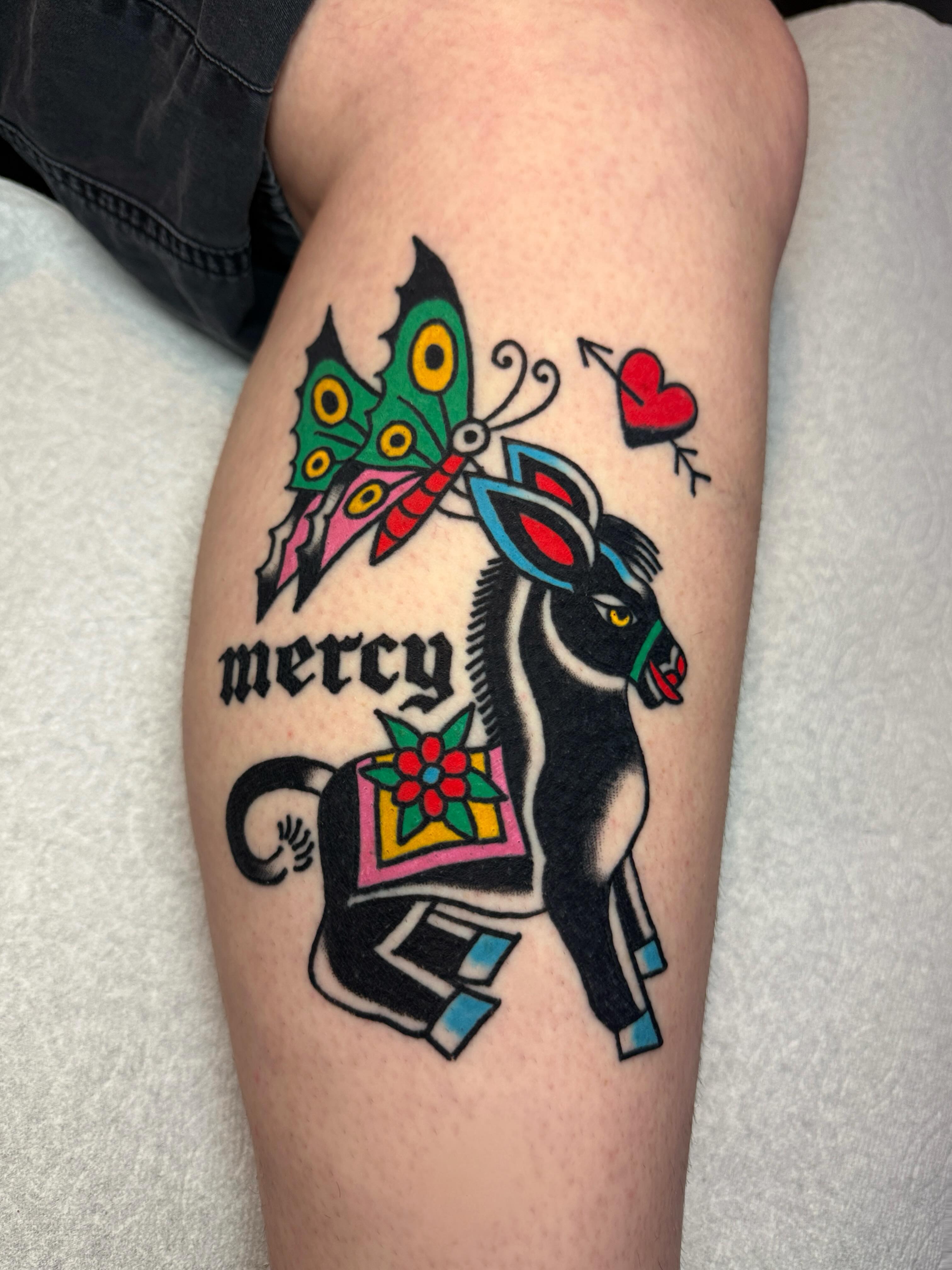 Donkey with butterfly American traditional tattoo on the thigh by Britt Kuechenmeister, Culver City, California