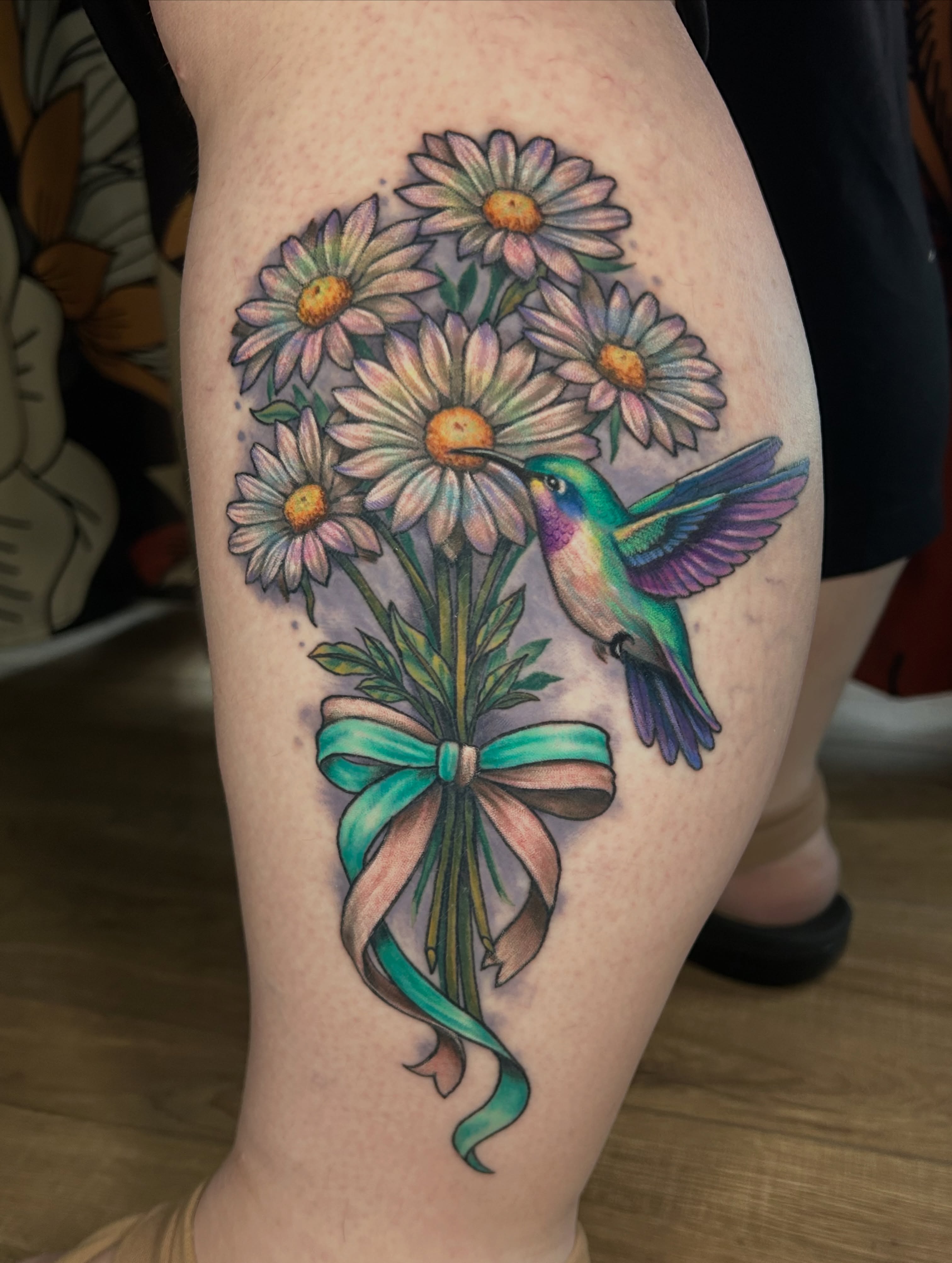 Hummingbird and daisies watercolor tattoo on the thigh by Paisley Diaz, Lombard, Illinois