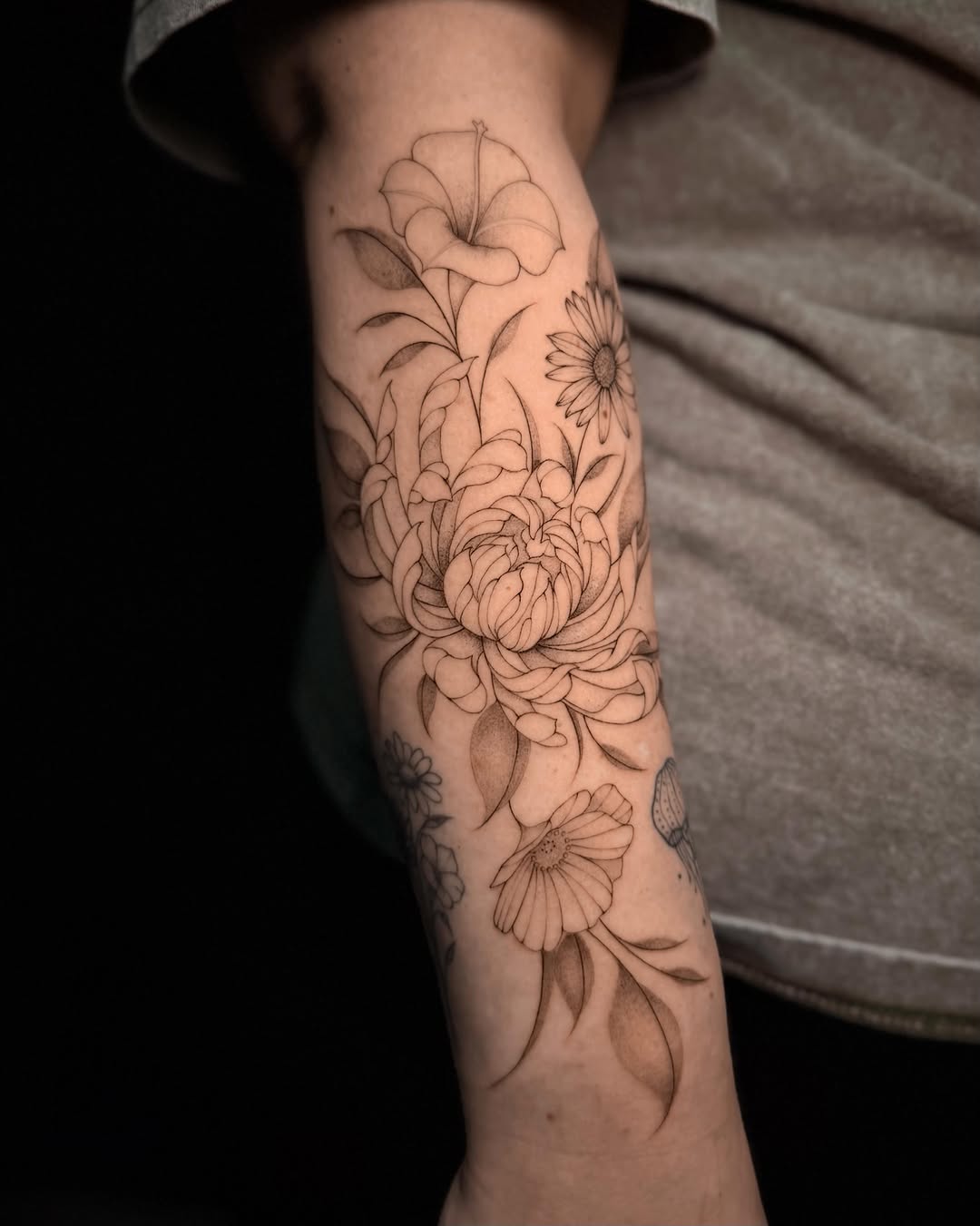 Floral arrangement fine line tattoo on the forearm by Frida Tattooista