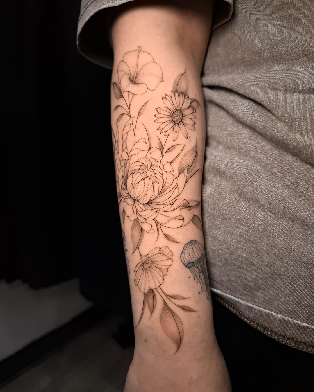 Flowers and jellyfish fine line tattoo on the forearm by Frida Tattooista