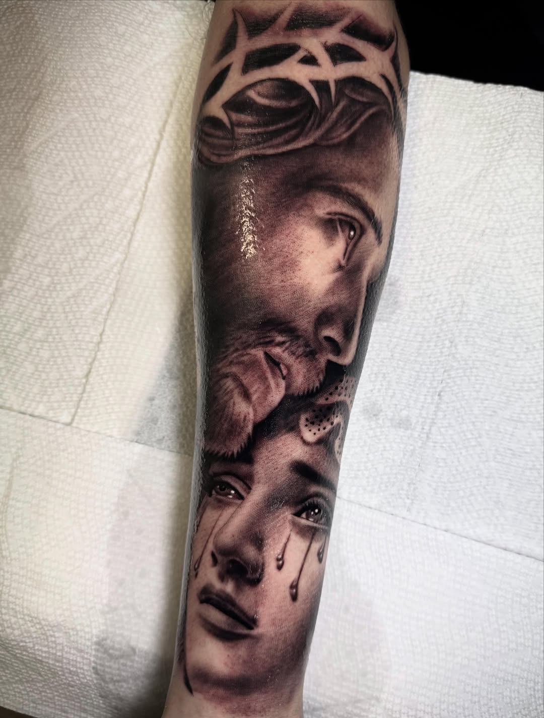 Jesus and crying woman Chicano tattoo on the forearm by Tony Garcia