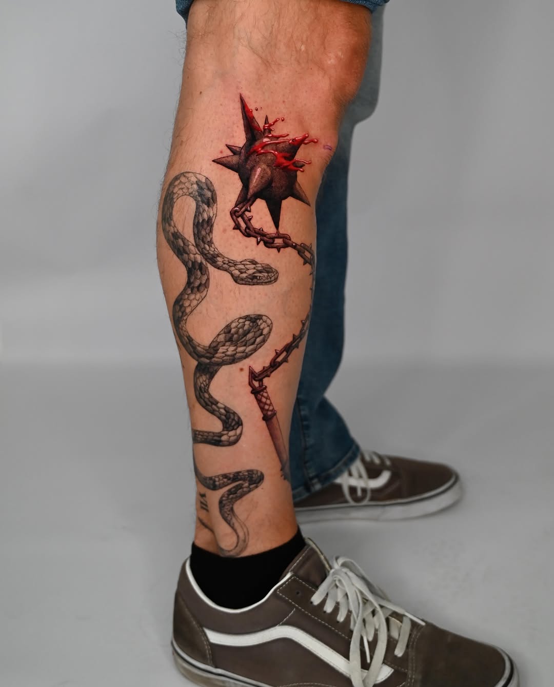 Snake, mace, and dagger surrealism tattoo on the calf by Andrew Flatts