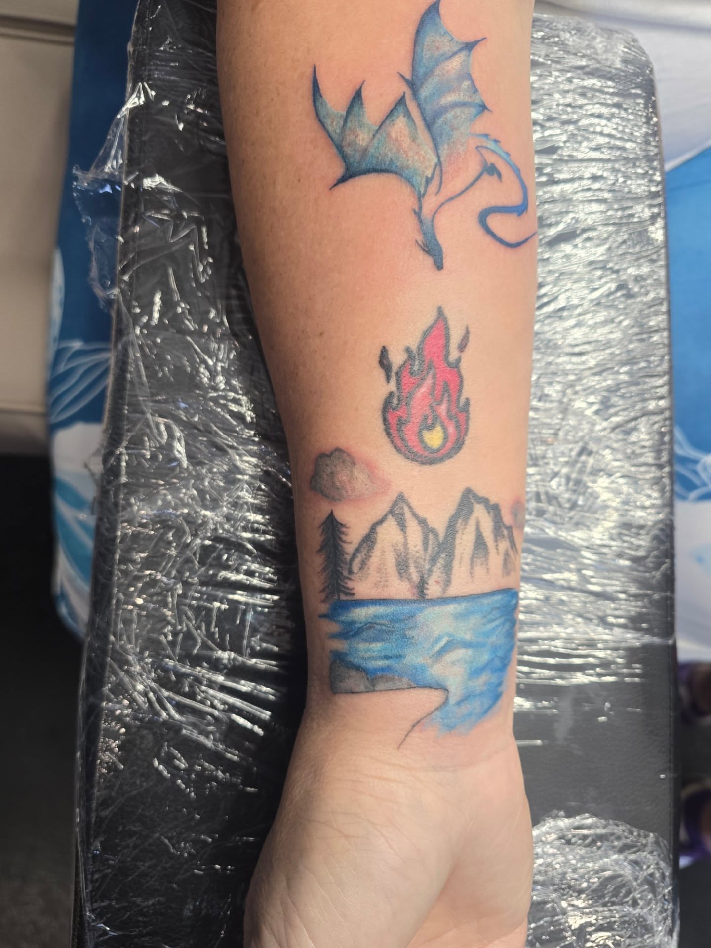 Dragon, flame, mountains, lake new school tattoo on the forearm by Maddox Kitson🕷