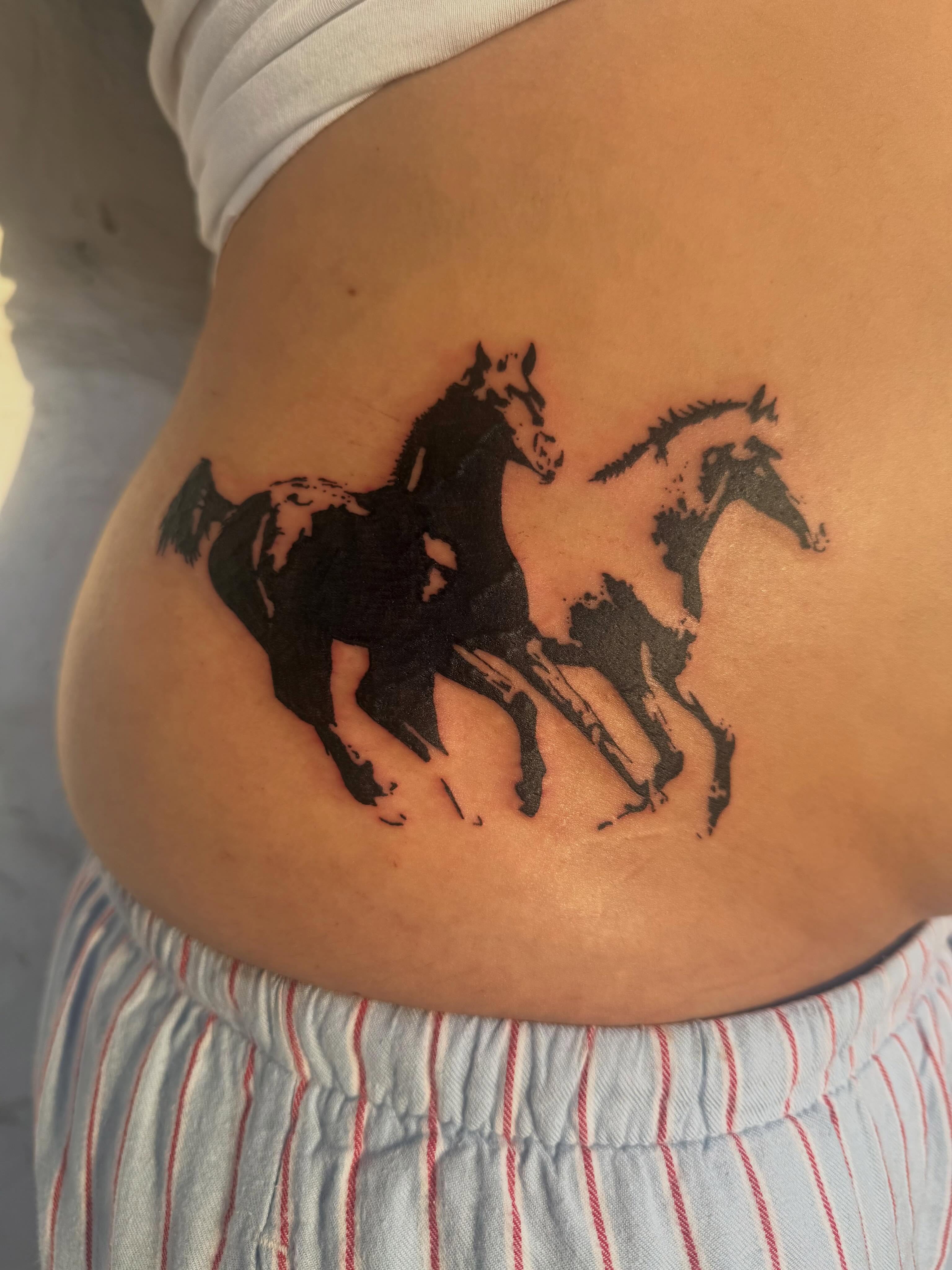 Horses black and grey tattoo on the torso by sarah