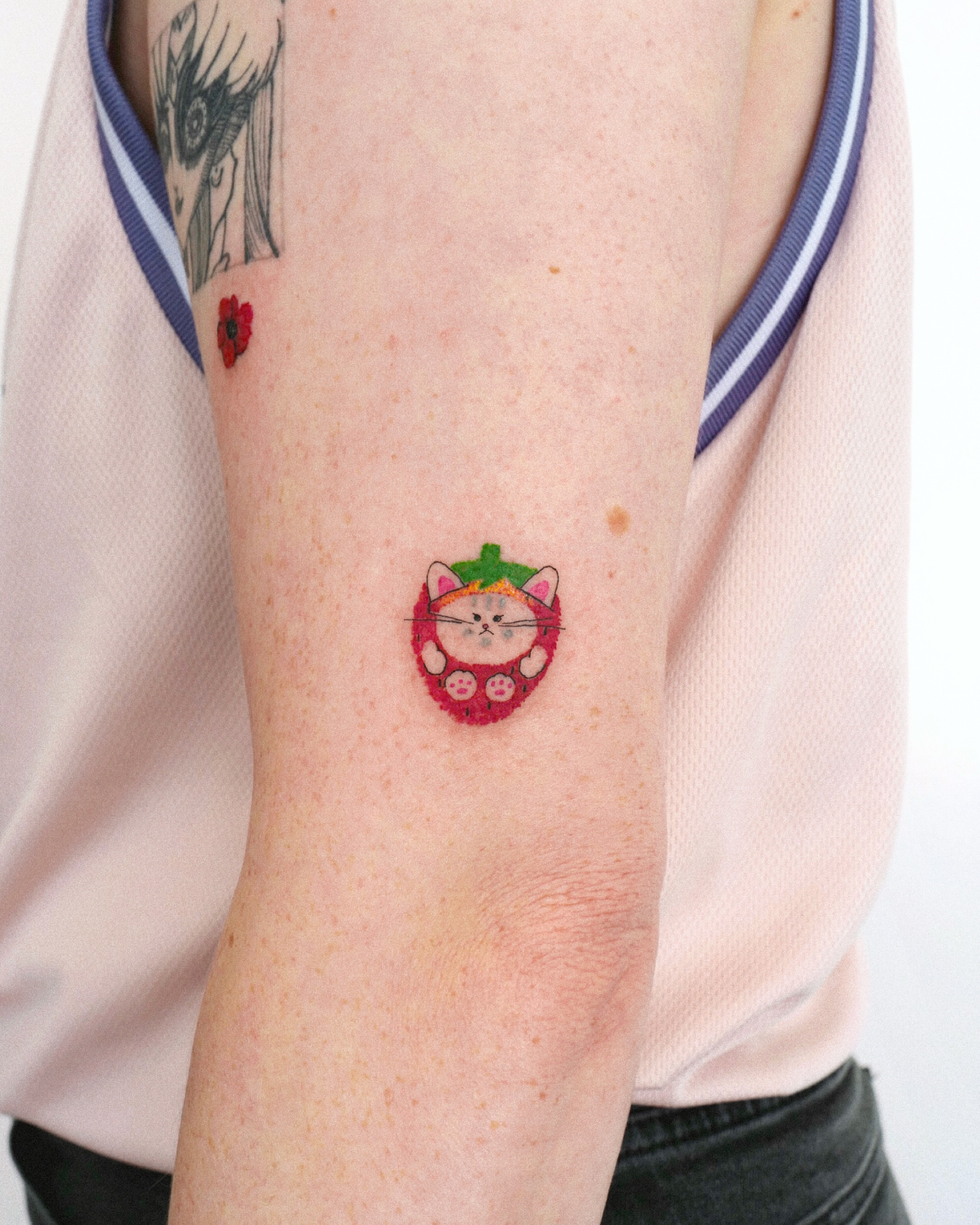 Cat in strawberry dotwork tattoo on the forearm by dahye lee